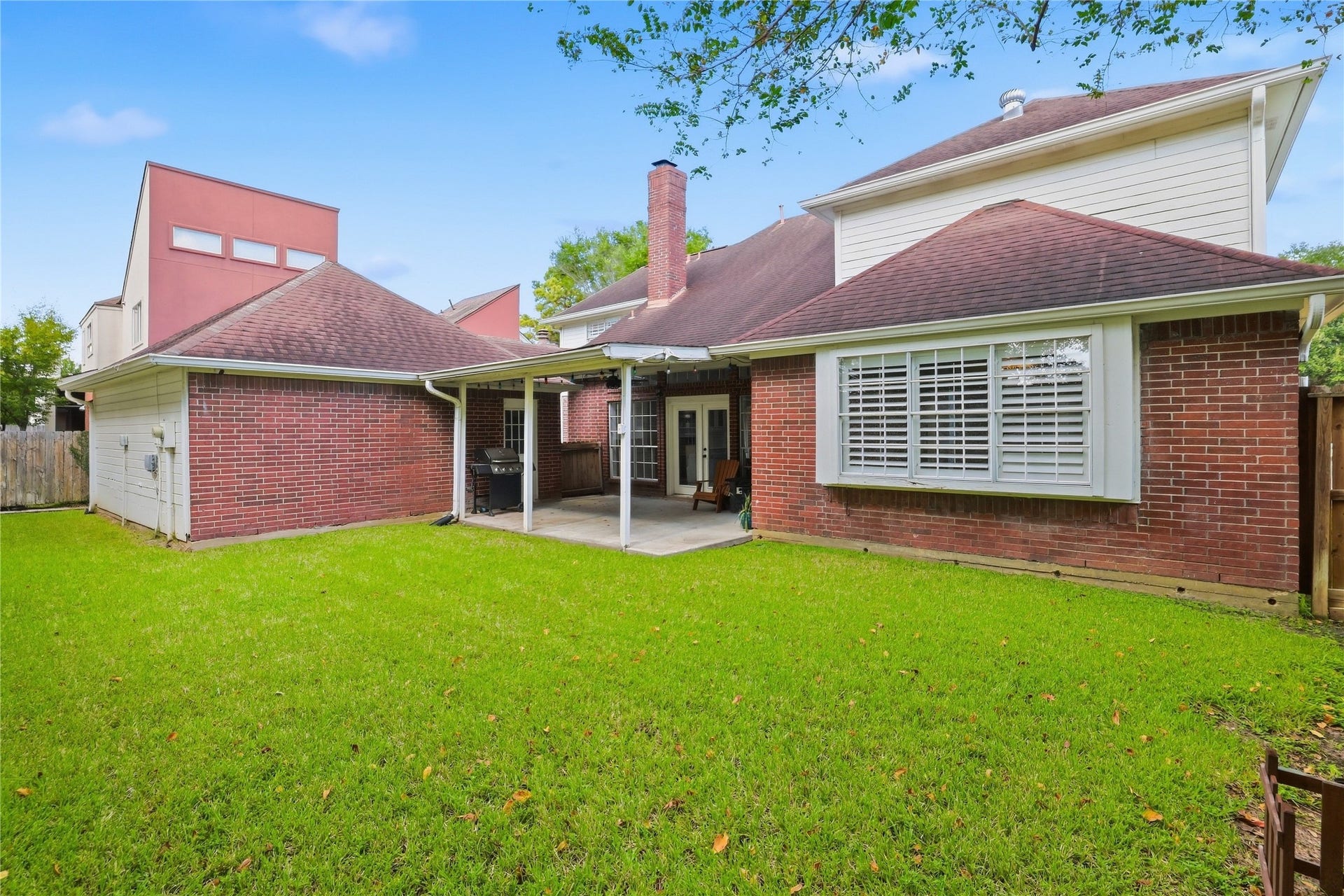 Spacious fenced backyard with lush green lawn, covered patio, and plenty of room for outdoor entertaining and recreation.