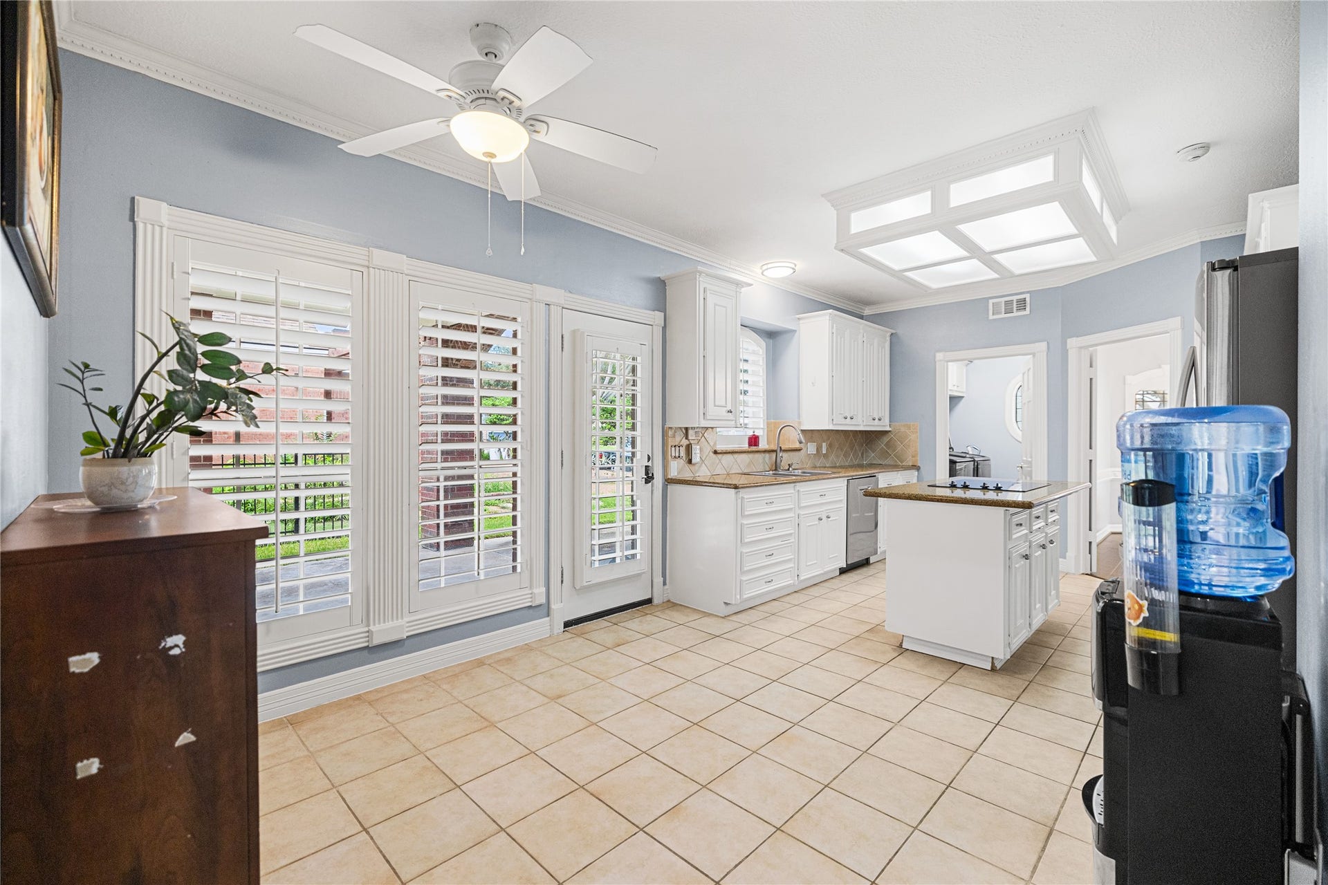 Bright breakfast area adjoining the kitchen, featuring plantation shutters, tile flooring, and convenient access to the side patio.