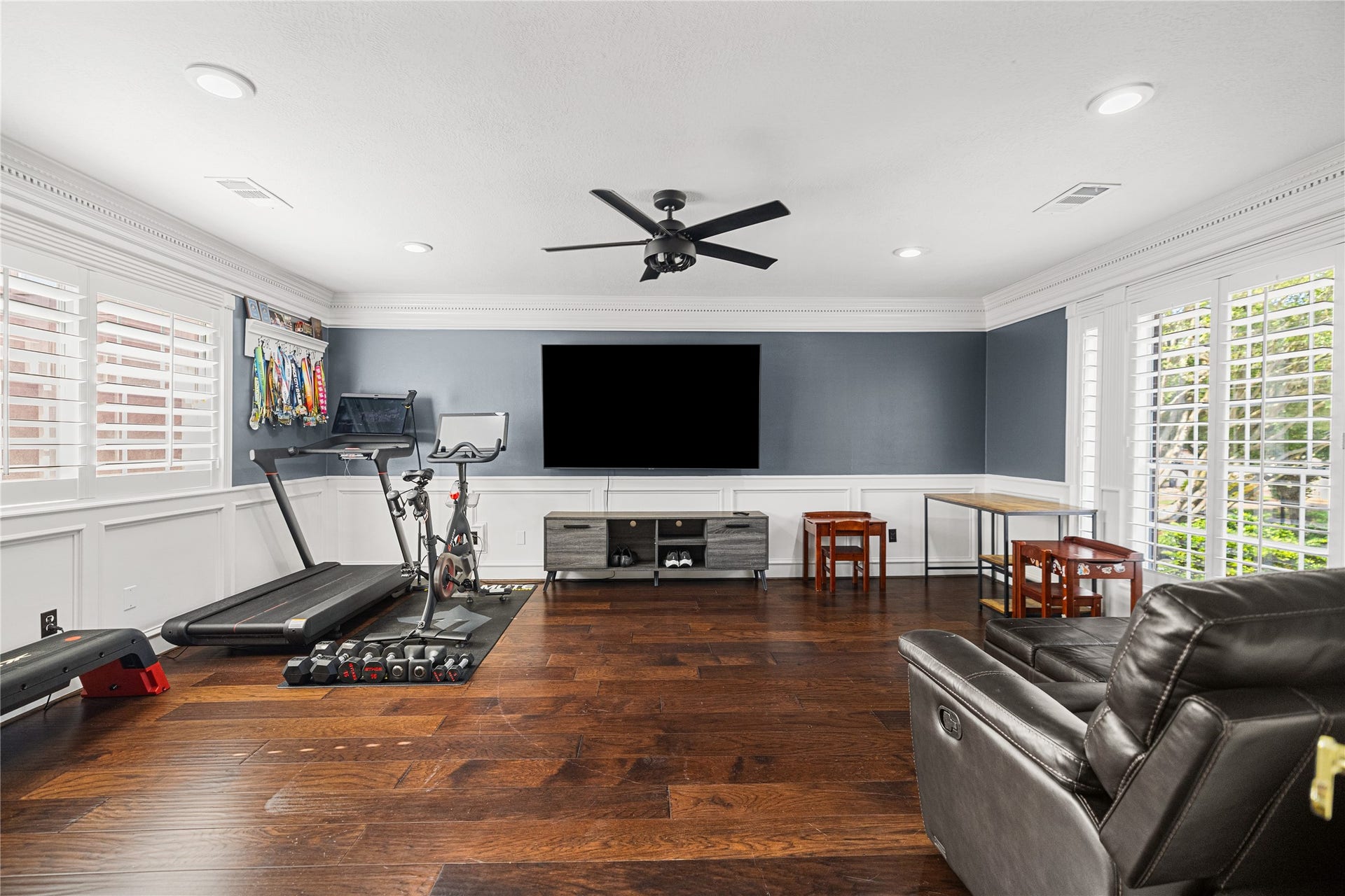 Impressive upstairs game room featuring engineered wood flooring, plantation shutters, and beautiful decorative wall molding.