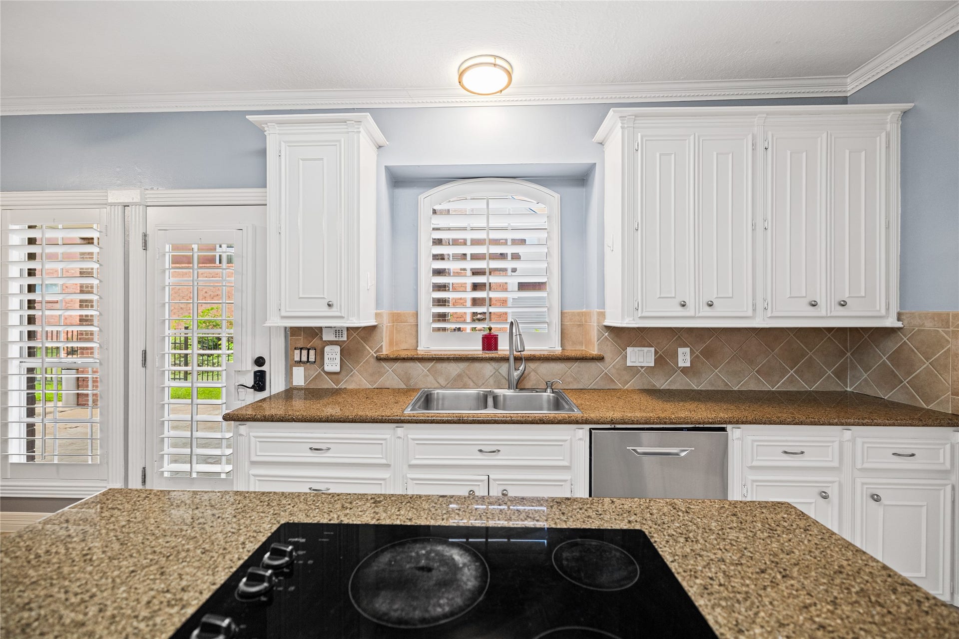 Kitchen island with electric cooktop, surrounded by generous countertop space, white cabinetry, and convenient access to the adjoining rooms.
