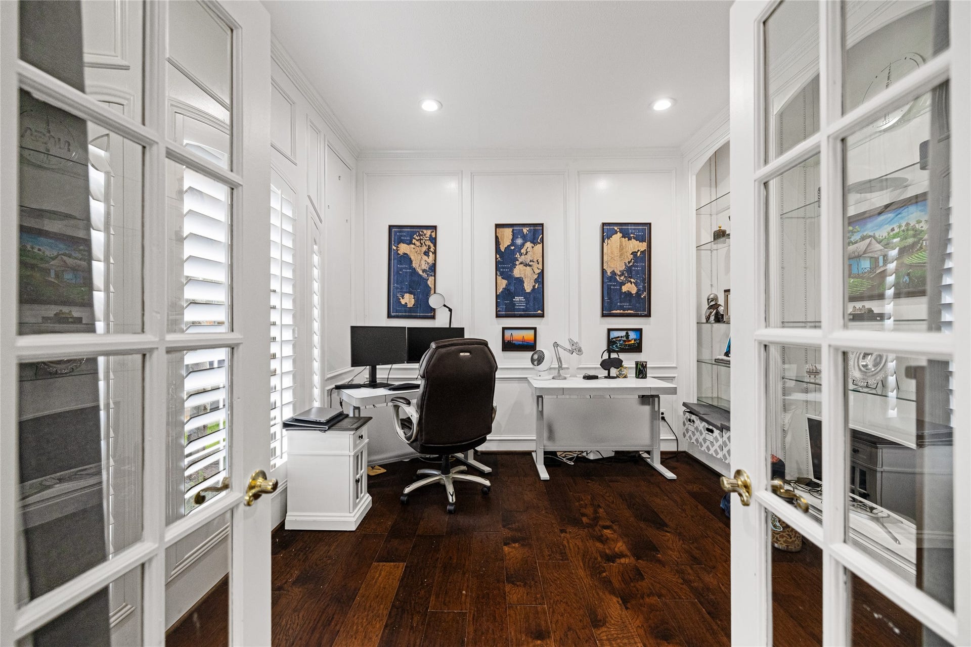 Private home office featuring French doors, rich wood flooring, plantation shutters, built-in cabinetry, and recessed lighting. Ideal for working from home!