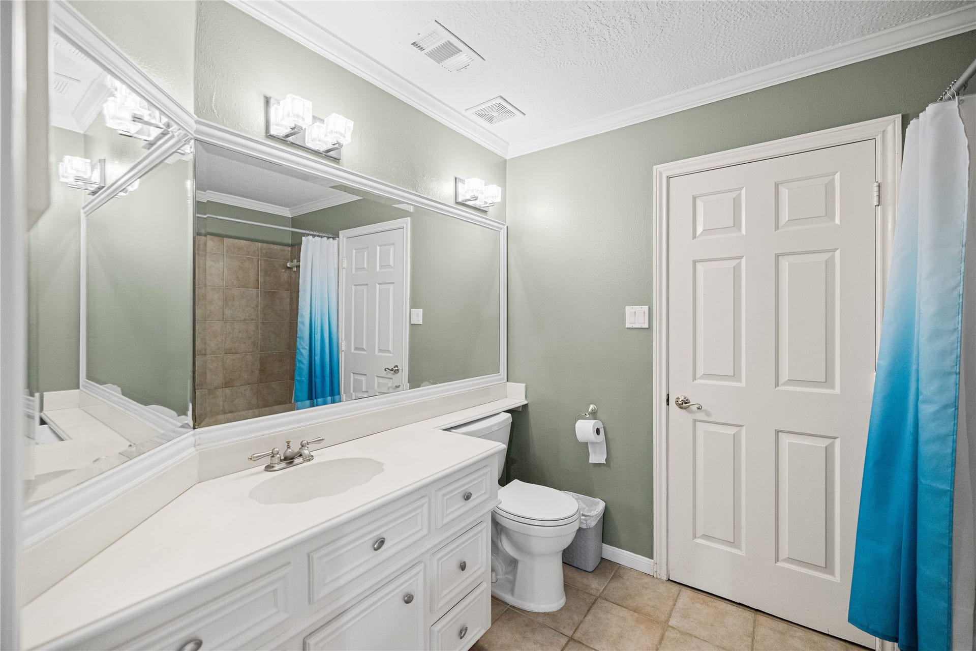 Additional bathroom with white cabinetry, spacious vanity, decorative lighting, and a tub/shower combination.