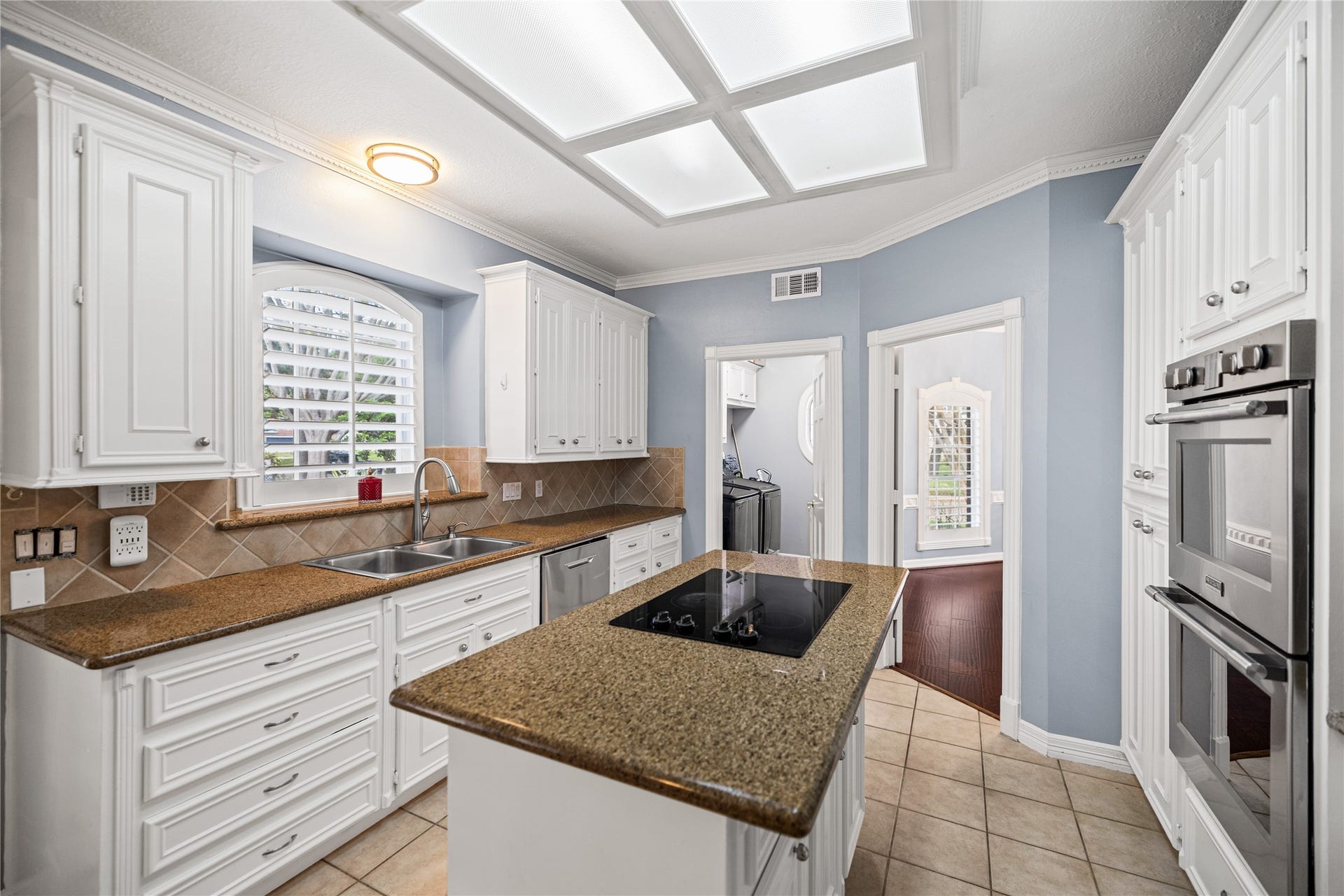 Another view of the kitchen highlighting the center island, double ovens, stainless steel refrigerator, and adjoining dining area.