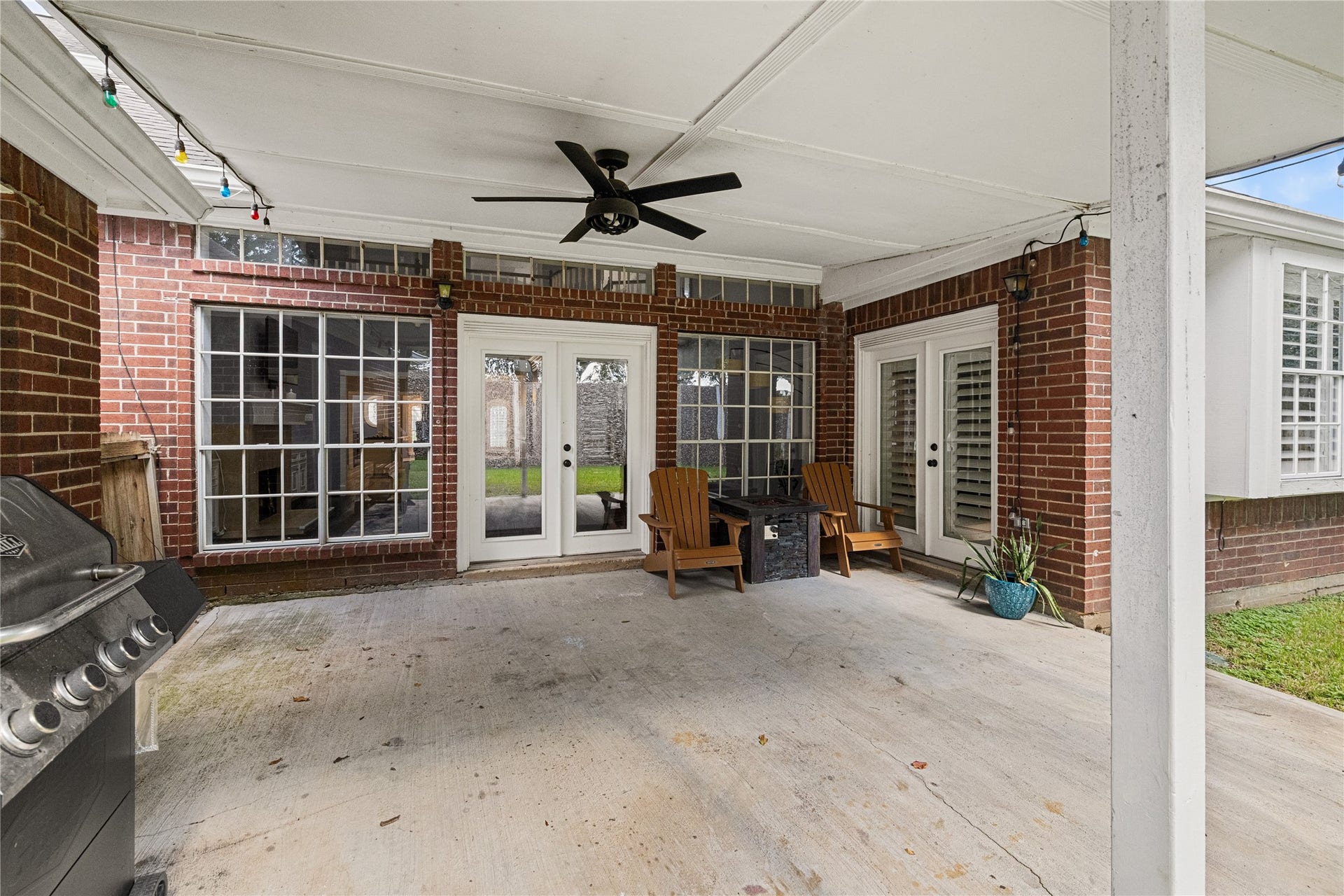Generously sized covered patio featuring a ceiling fan, outdoor lighting, and plenty of space for grilling, relaxing, and entertaining.