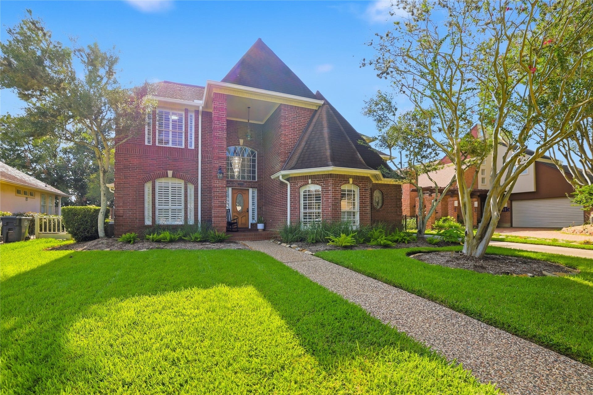 Beautiful Georgian-style brick exterior surrounded by mature trees, attractive landscaping, and a welcoming covered front entry.