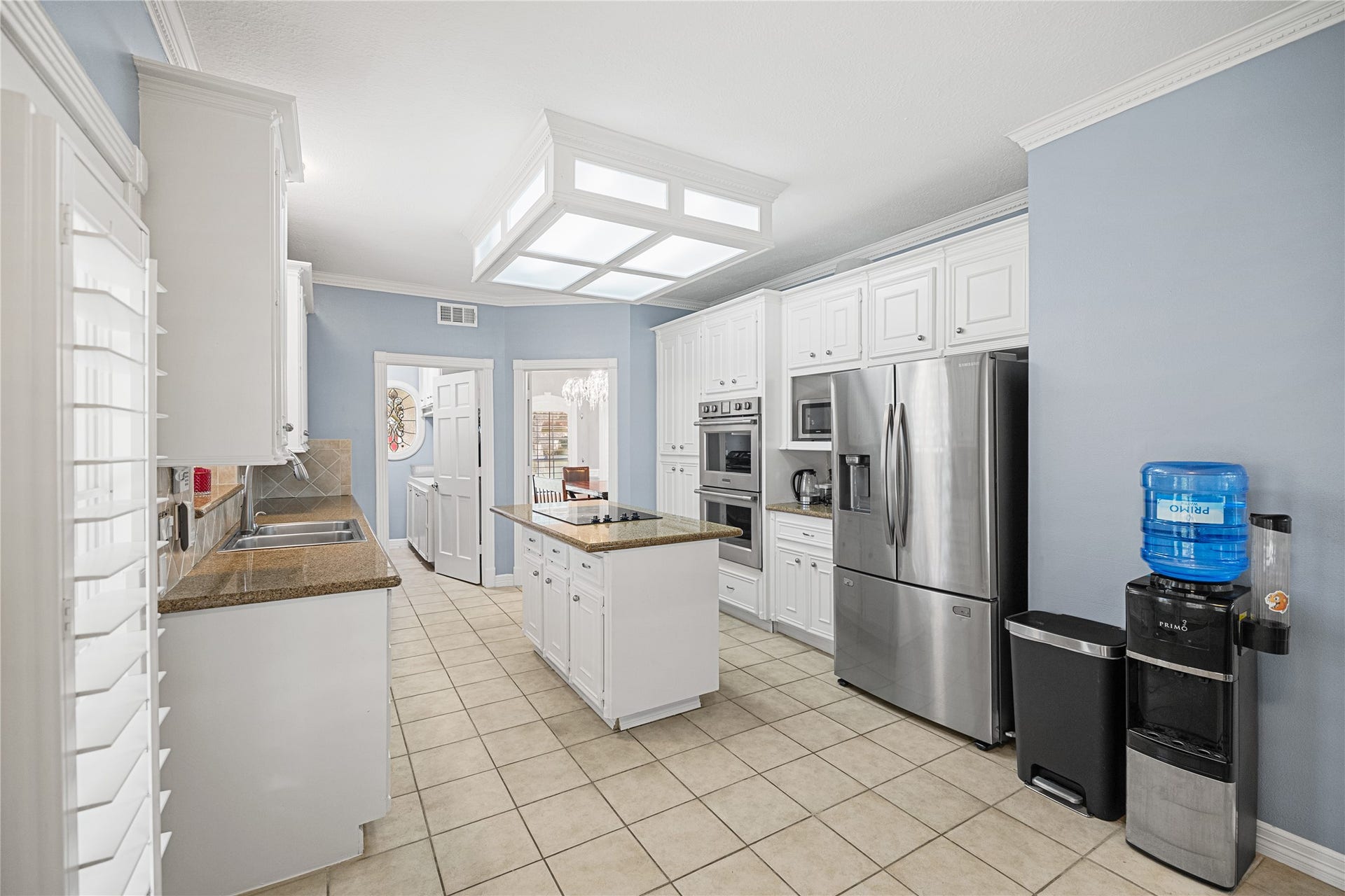 Bright kitchen with plantation shutters, Silestone countertops, stainless steel dishwasher, and an open connection to the breakfast area.