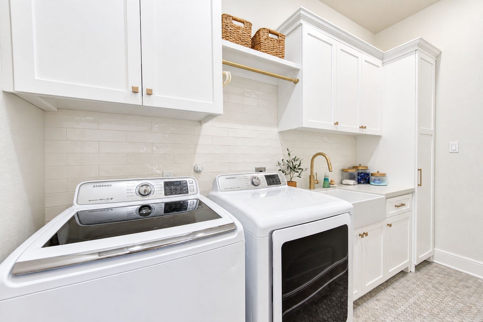 2803 Enriched Enclave Court, Richmond, TX 77406 Beautifully appointed laundry room featuring abundant custom cabinetry, quartz countertops, a farmhouse utility sink, stylish tile backsplash, hanging space, and generous storagemaking everyday laundry both functional and beautiful.
