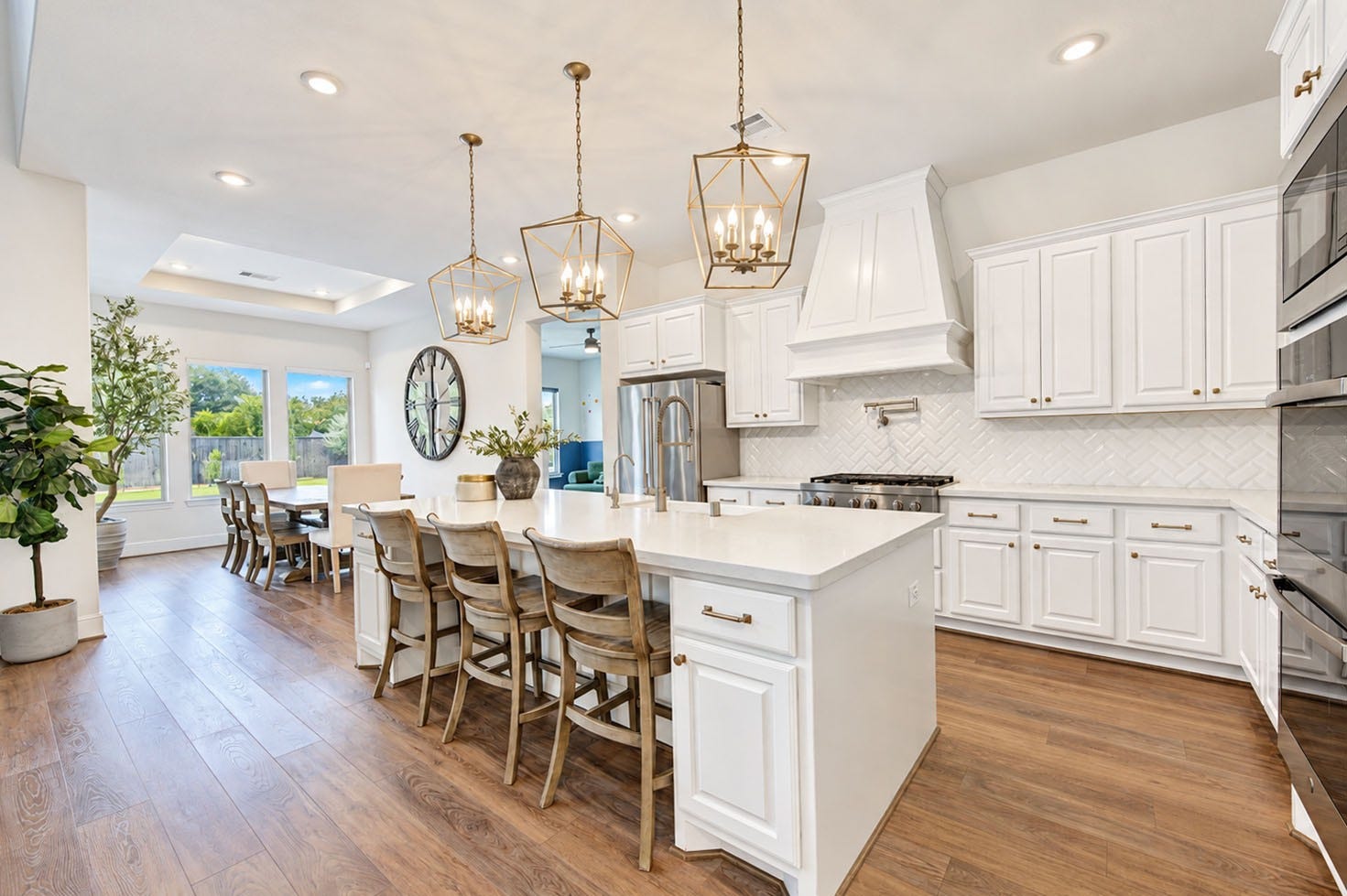 2803 Enriched Enclave Court, Richmond, TX 77406 Bright, elegant kitchen featuring an oversized island, abundant cabinetry, designer lighting, pot filler above the range, double wall ovens, and beautiful finishes.