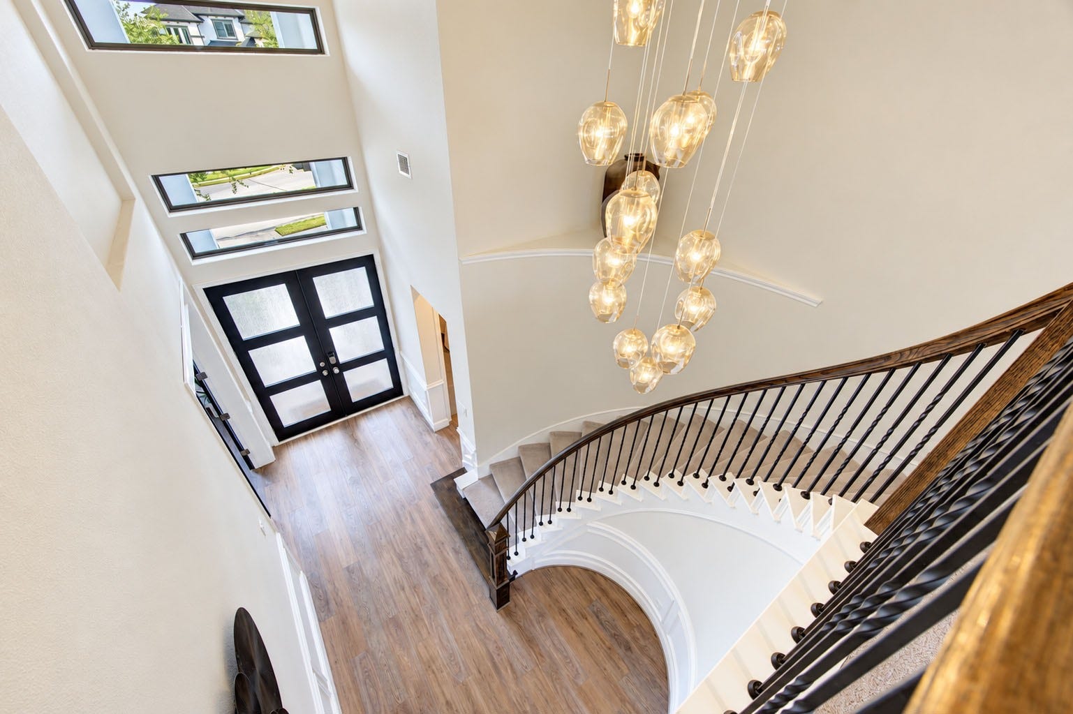 2803 Enriched Enclave Court, Richmond, TX 77406 Dramatic two-story entry featuring a sweeping curved staircase, modern statement chandelier, and striking black double doors.