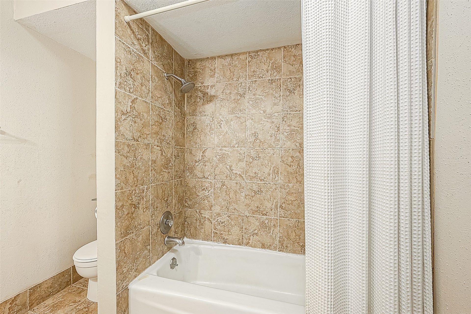 3131 Cummins Street, #54, Houston, TX 77027 Bath features a tub/shower combination with tiled surround & coordinating tile flooring.