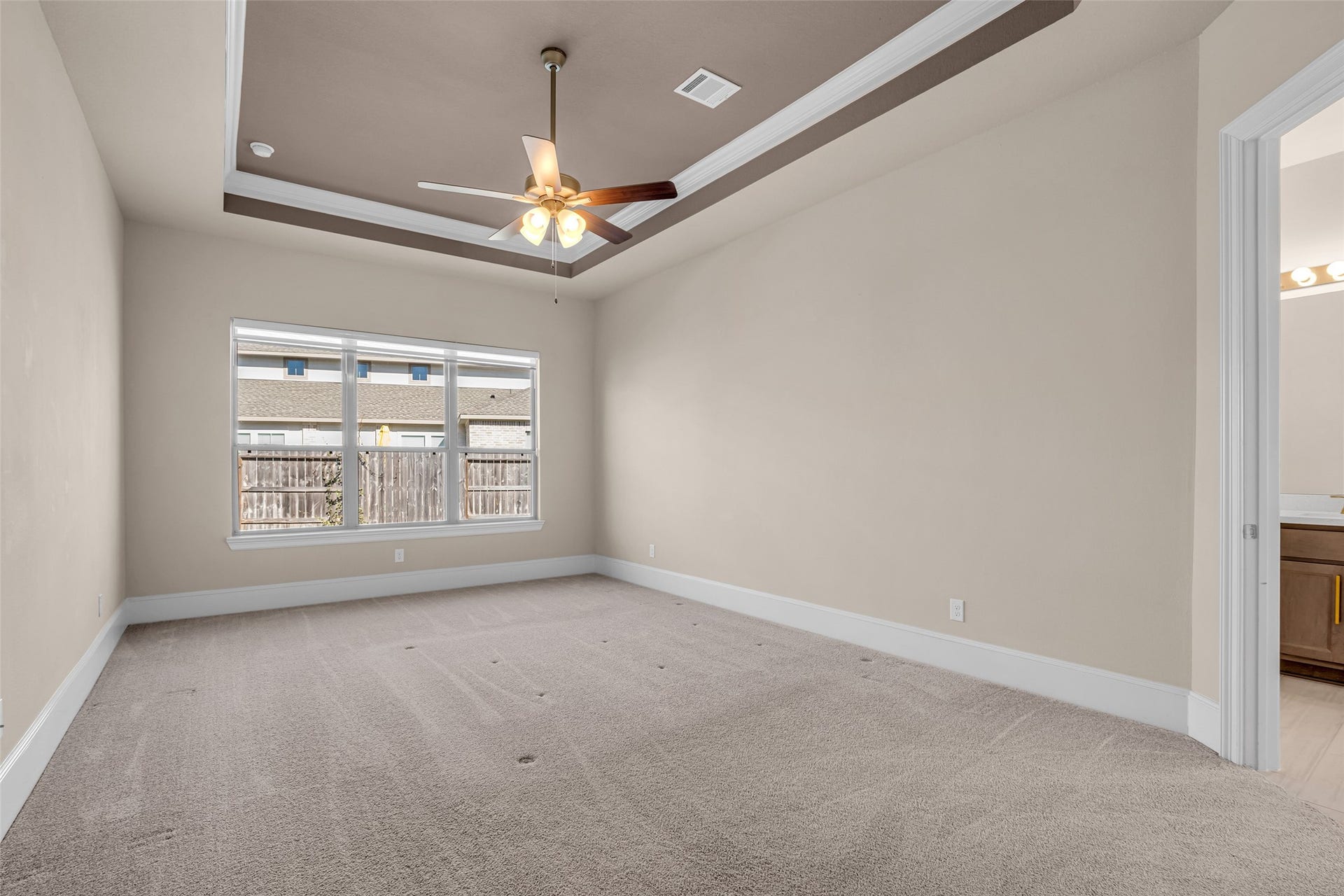 2718 Newbury Island Lane, Katy, TX 77493 The primary bedroom features large windows, a carpeted floor, and a tray ceiling, creating a spacious and inviting retreat.
