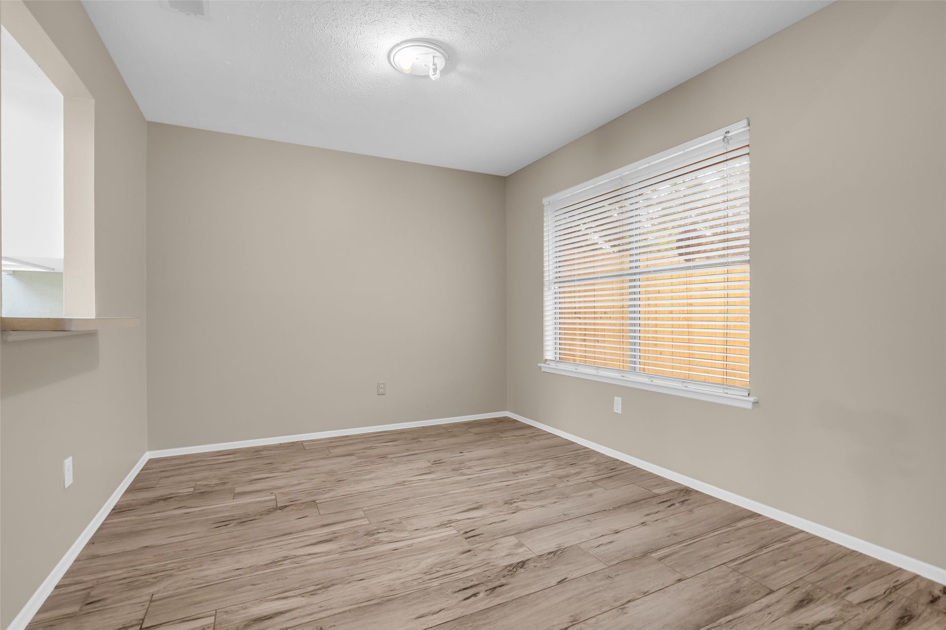 11827 Brook Meadows Lane, Meadows Place, TX 77477 This Third bedroom features neutral walls, wood-look flooring, and a large window with blinds that lets in natural light, creating a bright and versatile space.