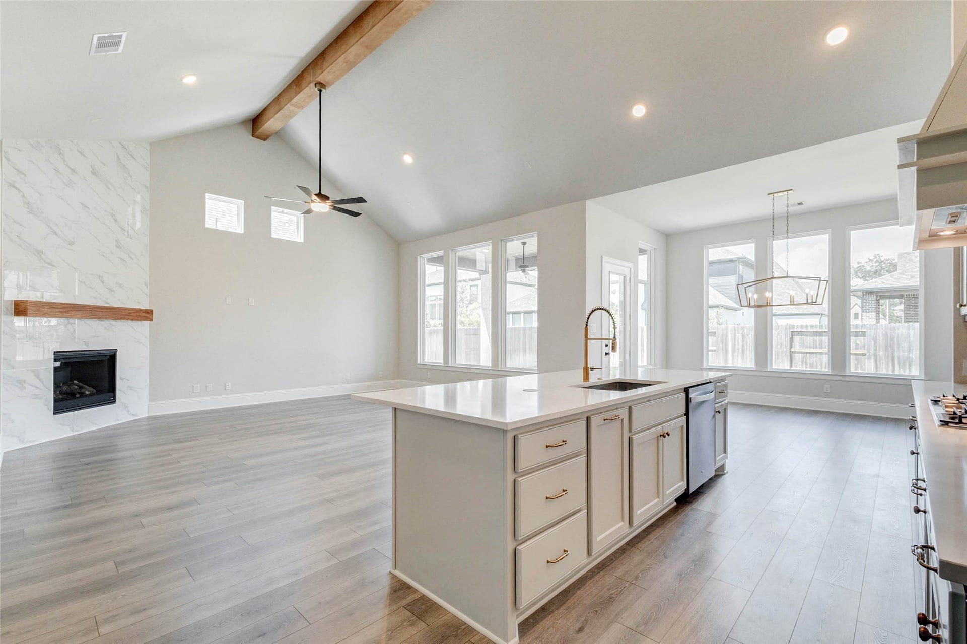 Open-concept living space features high ceilings with wooden beam, and large windows for natural light.