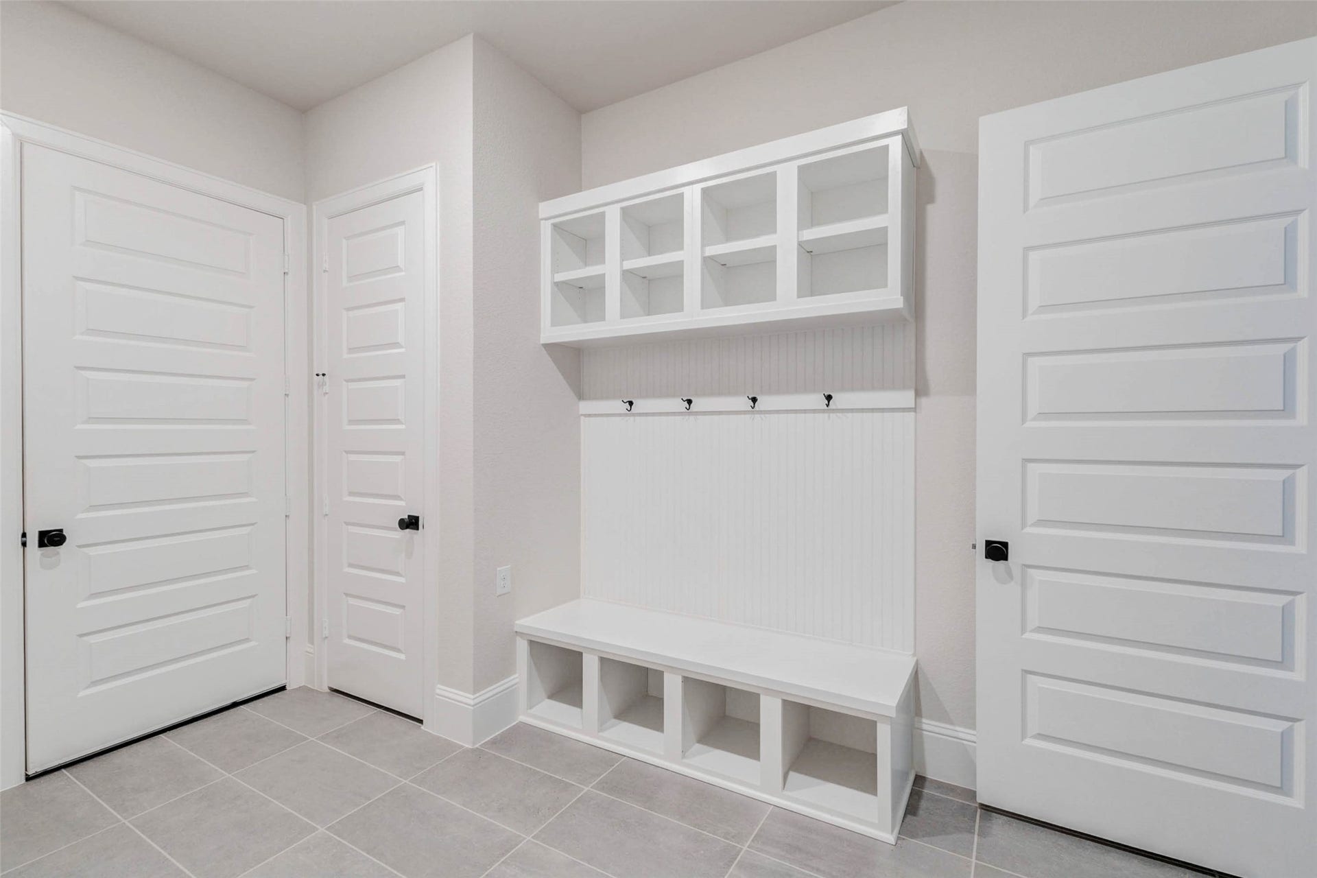 Large MUD drop space features built-in shelving and storage cubbies, a bench, and wall hooks for convenience. The space is bright with neutral tones making it both functional and stylish for everyday use.