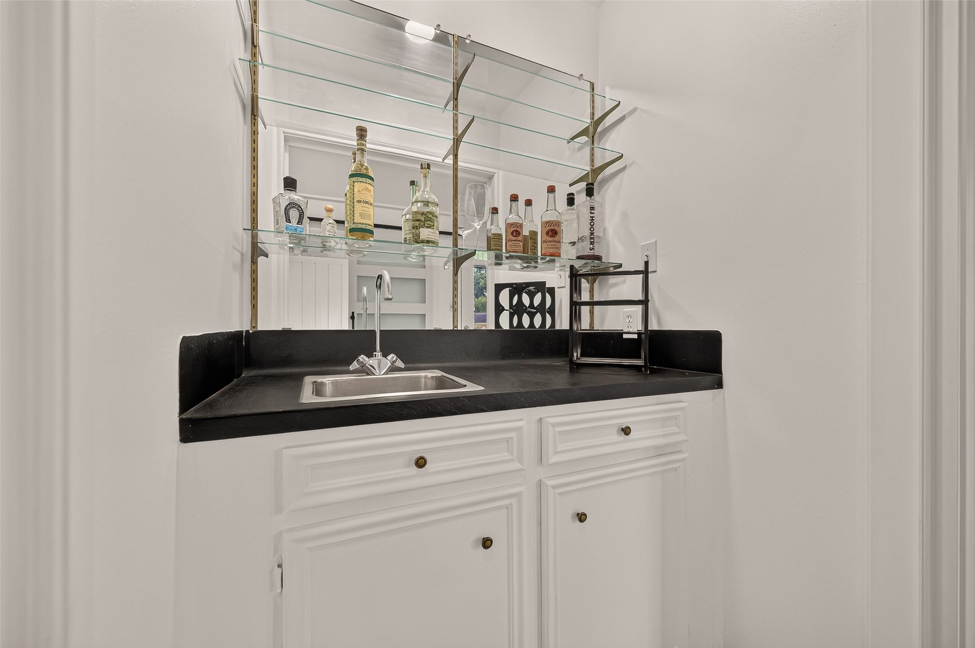 2230 S Fountain Valley Drive, Missouri City, TX 77459 Wet bar with black granite, built-in sink, and mirrored shelving, perfect for entertaining.