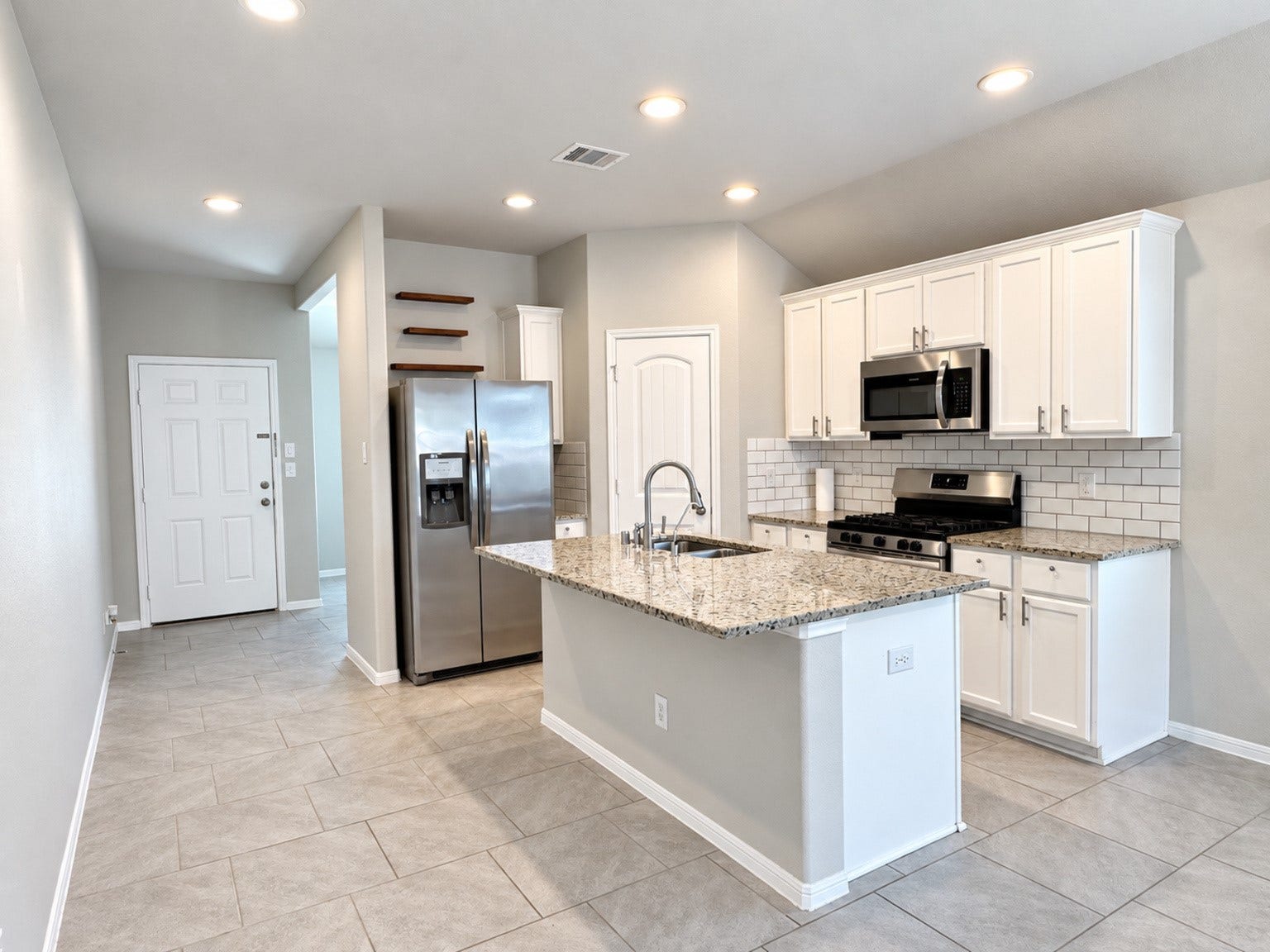 29202 Dunns Creek Court, Katy, TX 77494 Kitchen featuring white cabinetry, granite countertops, stainless steel appliances, and a subway tile backsplash.