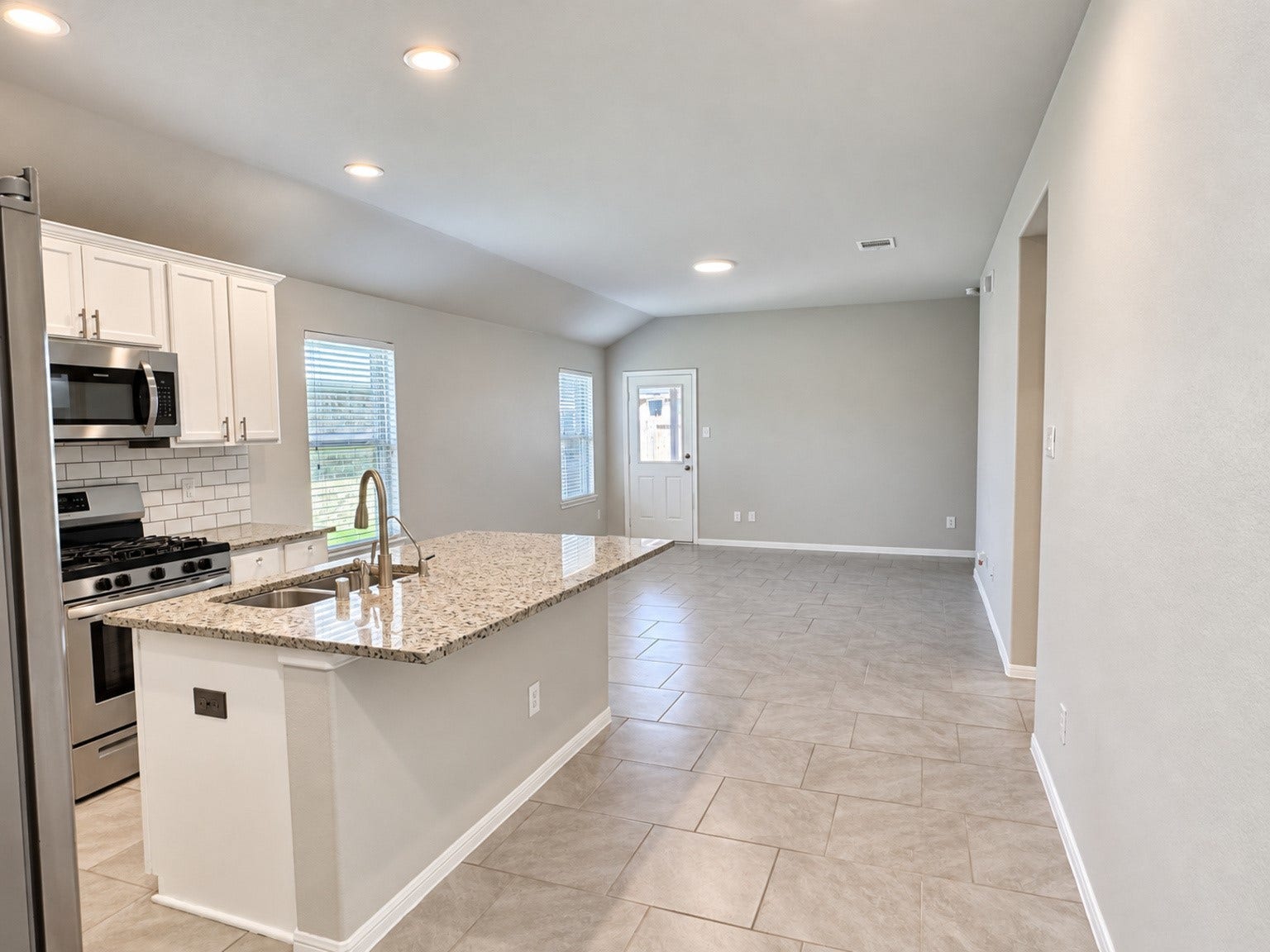 29202 Dunns Creek Court, Katy, TX 77494 Open kitchen overlooking the living area, with a granite island and tile flooring extending throughout the space.