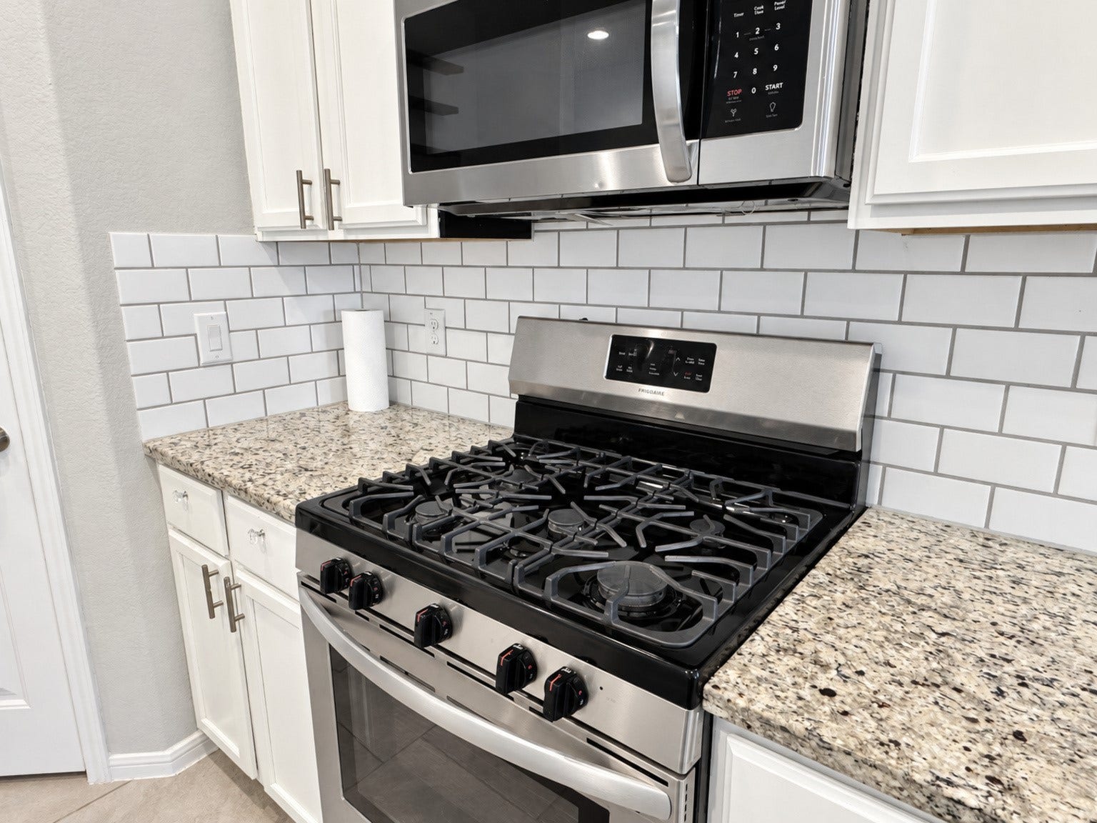 29202 Dunns Creek Court, Katy, TX 77494 Gas range and over-the-range microwave framed by granite countertops and a subway tile backsplash.
