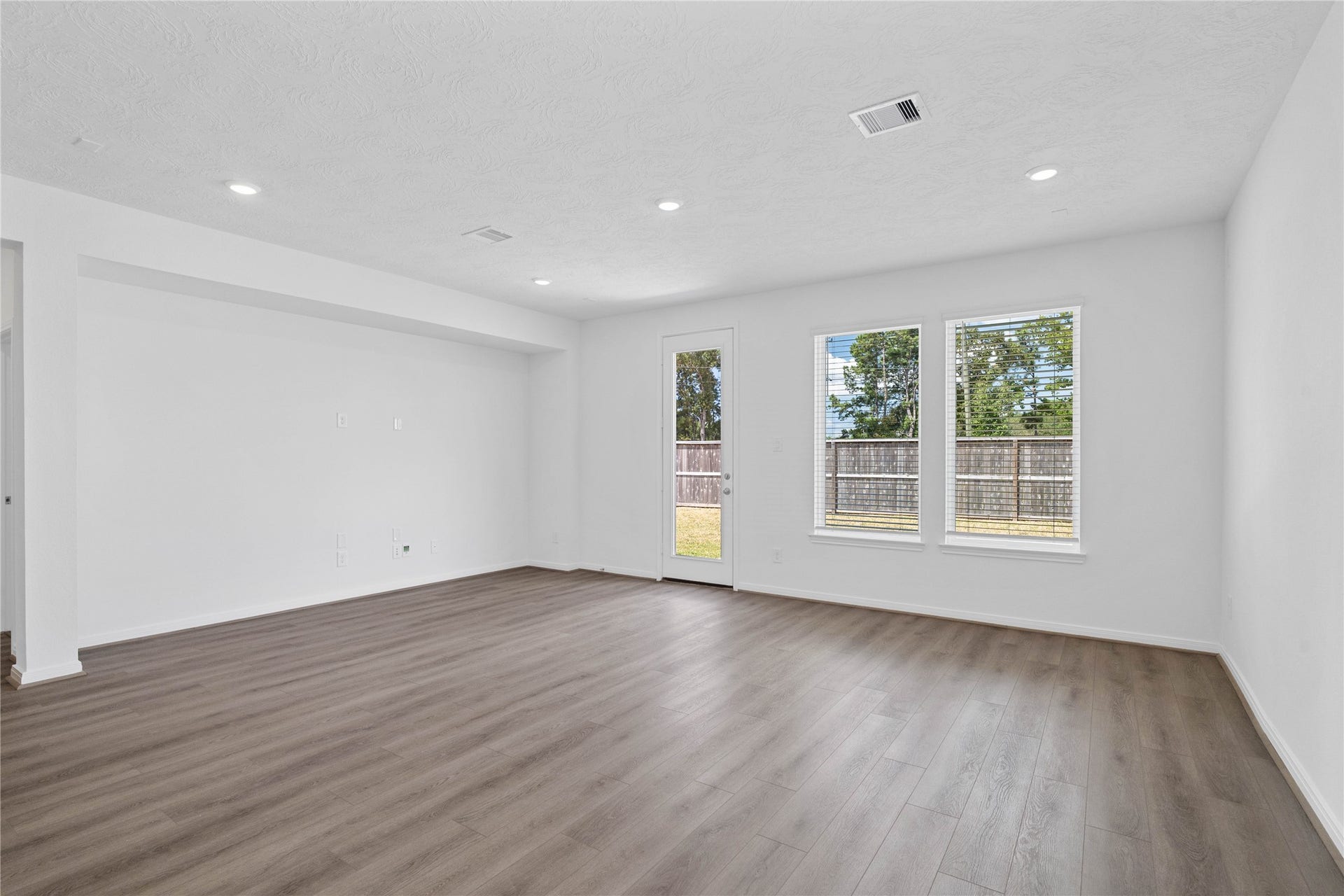 Sun-drenched living room boasting a dedicated architectural niche for seamless TV mounting and media storage.