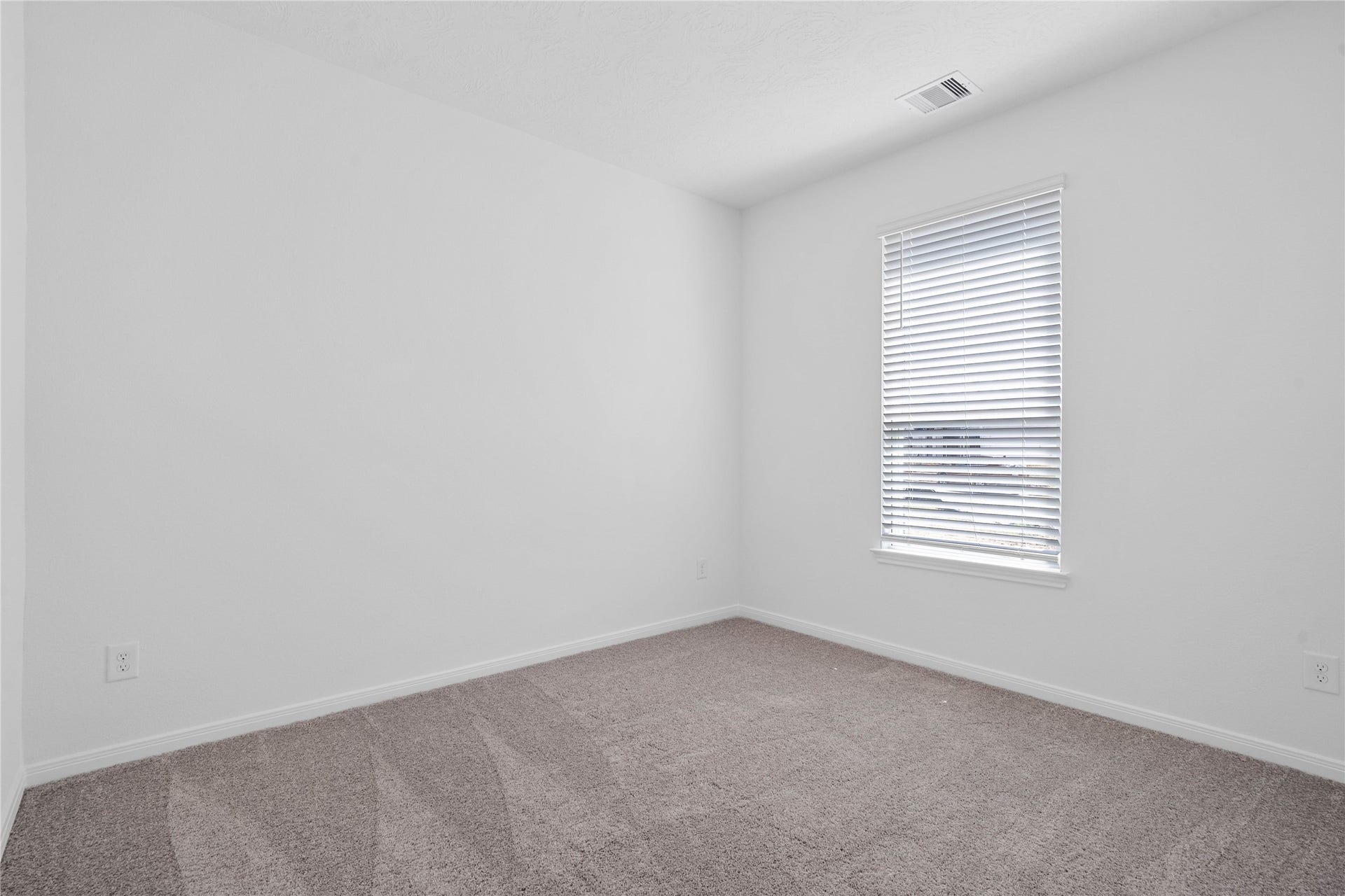 This secondary bedroom offers comfort and style with plush carpeting, neutral paint tones, recessed lighting, a large window with blinds, and a generously sized closet.