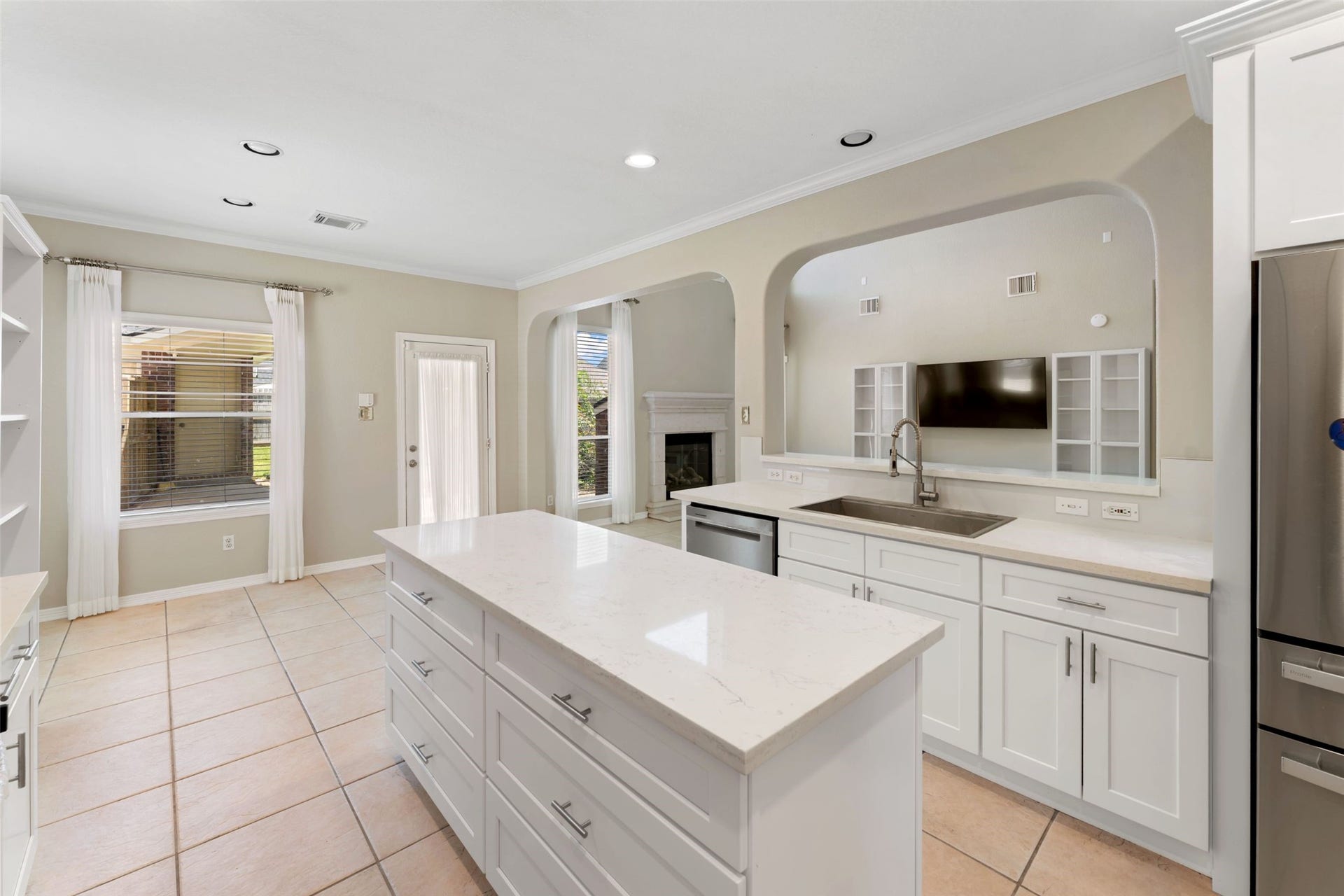 Open concept kitchen and living area featuring a large island, extensive cabinetry, stainless appliances, and an open view into the living room.