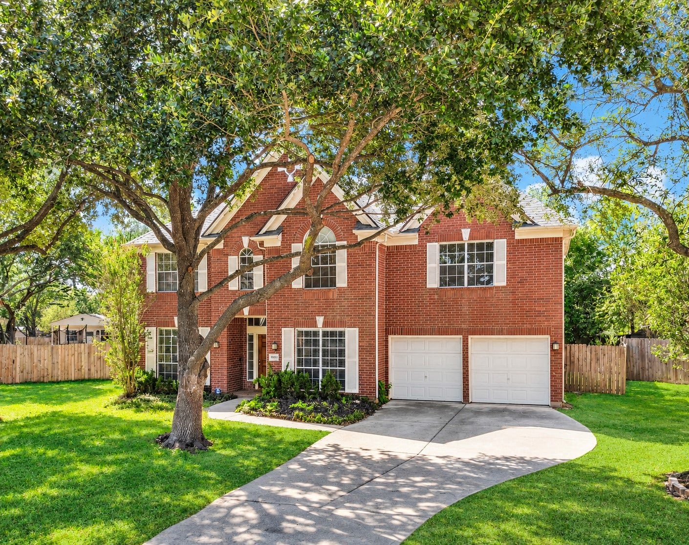 10003 Briarpark Trail Lane, Houston, TX 77064 This view highlights the home's classic red brick exterior, attractive architectural details and beautifully framed windows, all beneath a canopy of mature trees.