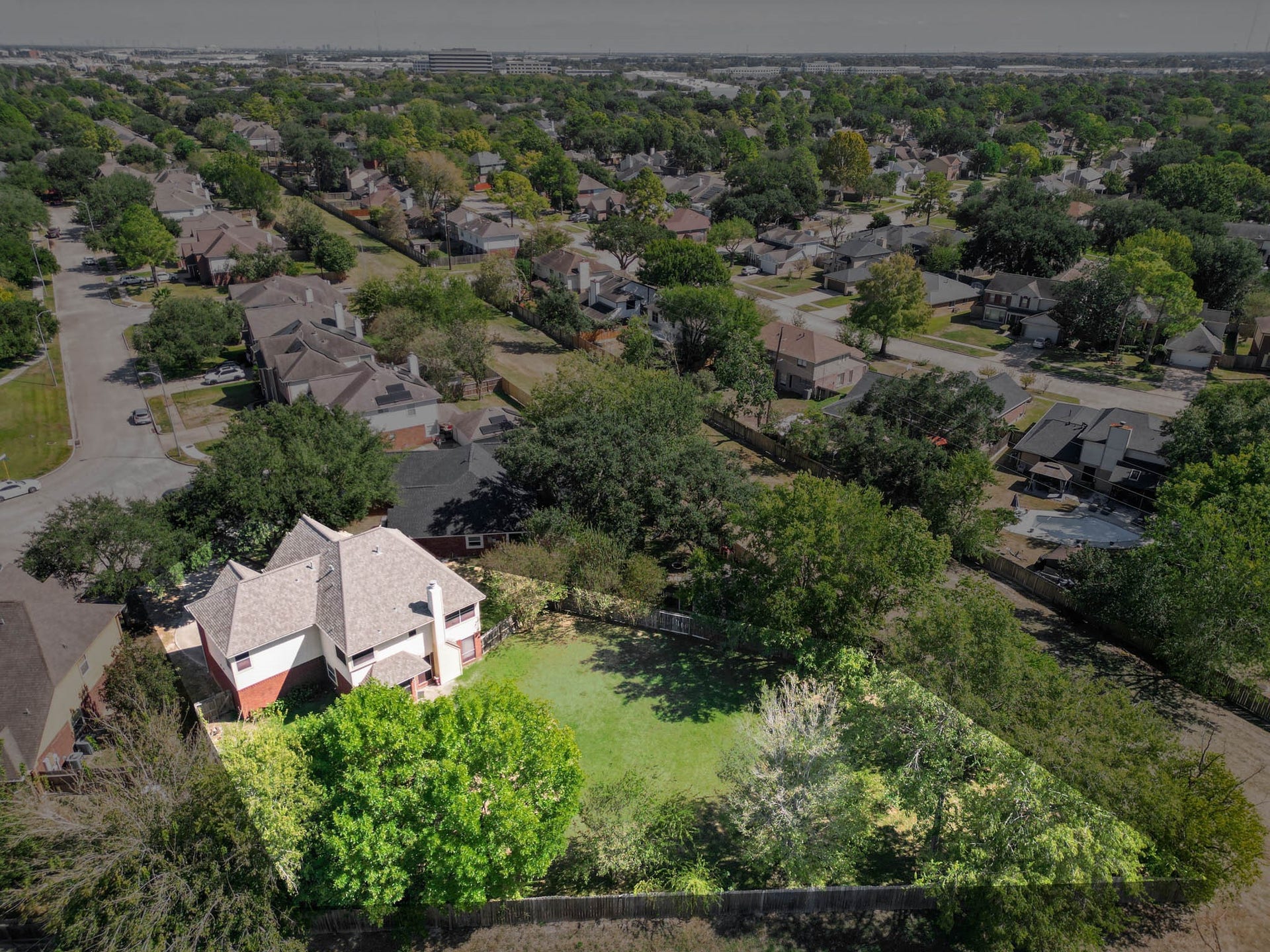 10003 Briarpark Trail Lane, Houston, TX 77064 Aerial perspective highlights the home's setting among mature trees and the impressive backyard extending behind the property.