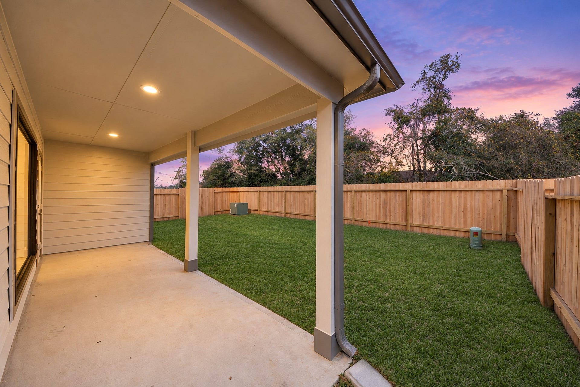 Spacious covered patio overlooking a lush, fenced backyard, perfect for outdoor relaxation and entertainment.