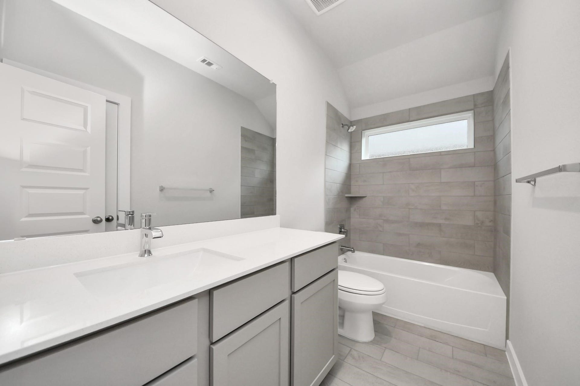 Bright and modern bathroom featuring sleek tiles, a spacious vanity, and a large mirror, creating a fresh and inviting space.