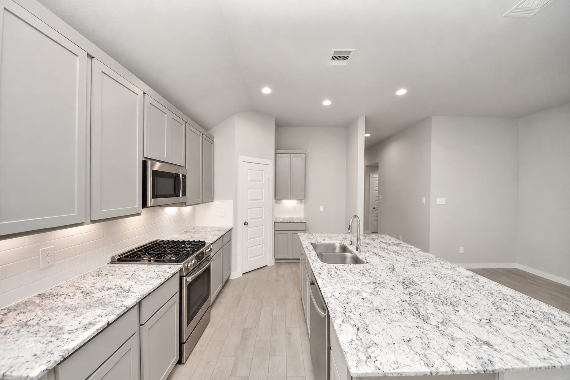 Sleek kitchen with modern gray cabinetry, granite countertops, and stainless steel appliances, featuring a spacious island perfect for entertaining.