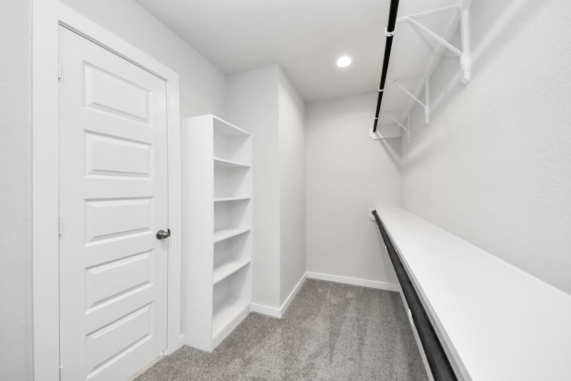 Spacious walk-in closet with built-in shelving and ample hanging space, perfect for organized storage.