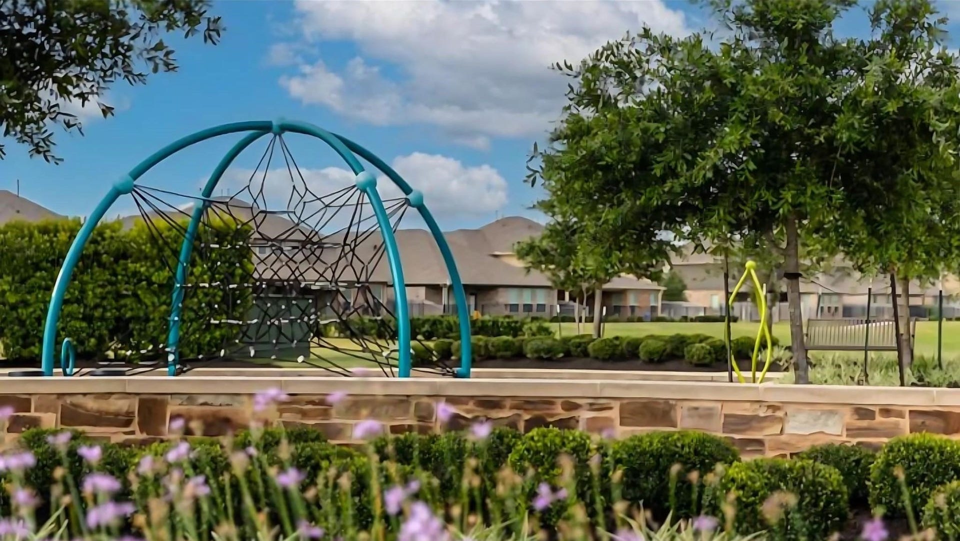 Charming community playground with modern climbing structure, lush greenery, and nearby homes, perfect for family living.