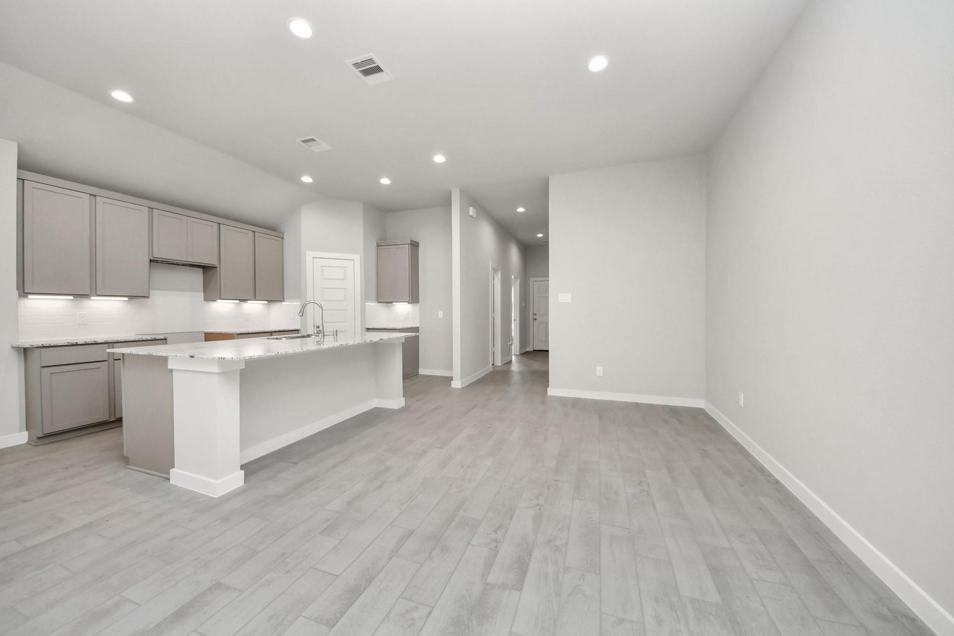 Bright and spacious open-concept kitchen and living area featuring modern cabinetry, sleek countertops, and elegant flooring.