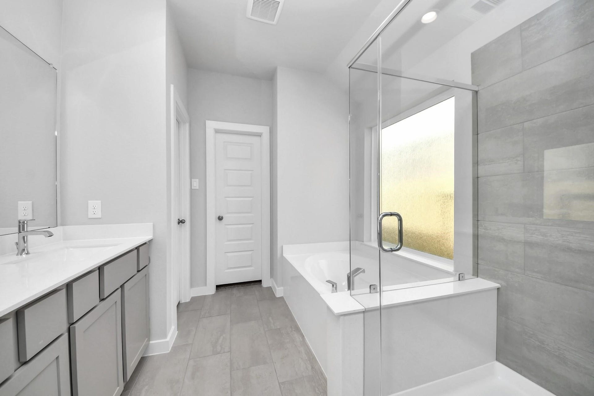Bright and modern bathroom featuring a spacious glass-enclosed shower, sleek dual vanities, and elegant tile flooring for a luxurious feel.
