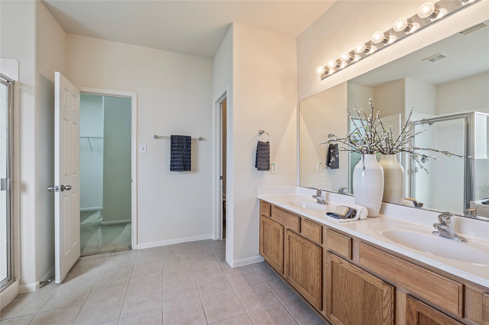 4404 Cypress Meadows Court, Dickinson, TX 77539 The primary bath offers double vanities, a large mirror, tile flooring and access to the walk-in closet.