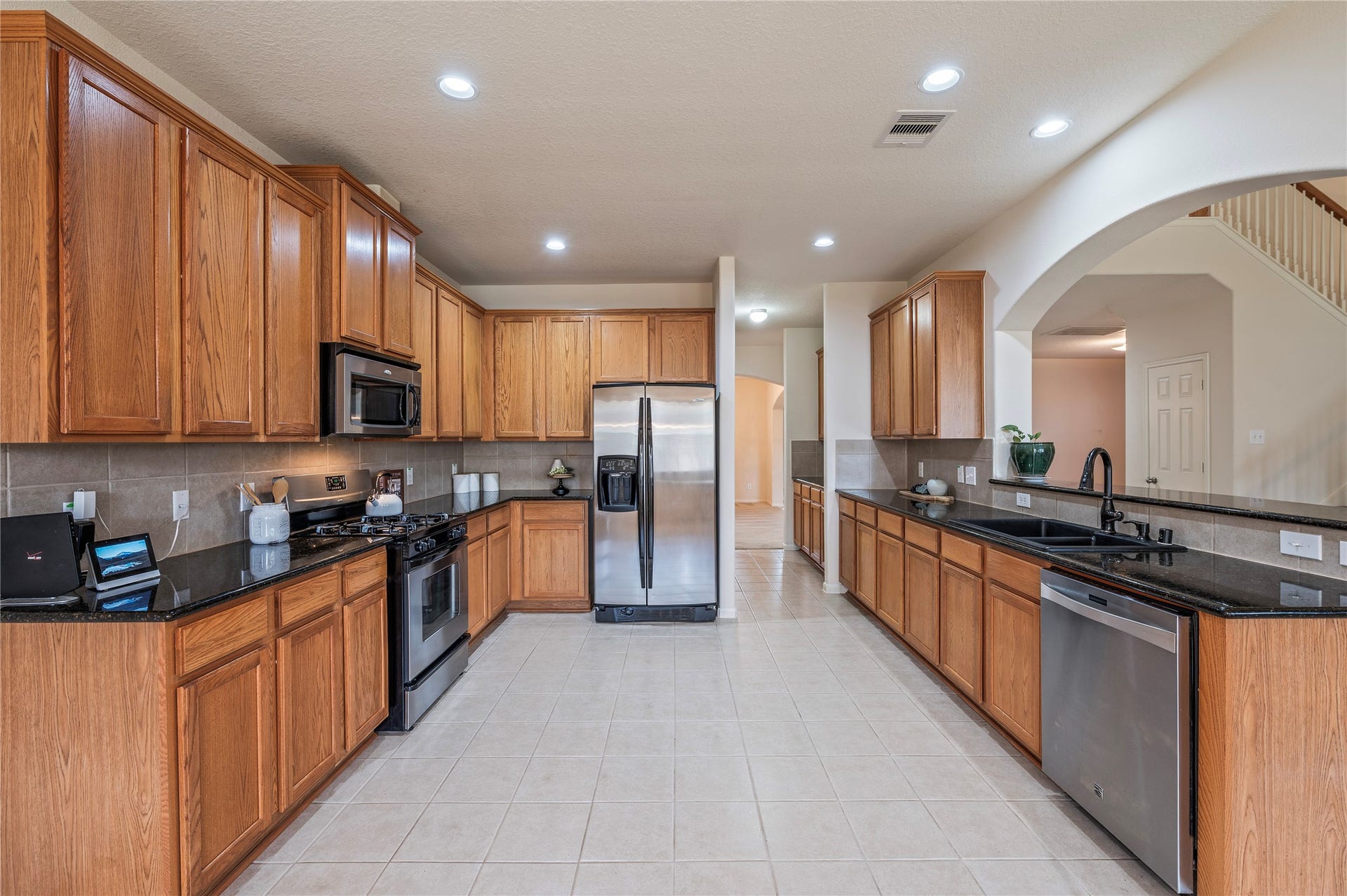4404 Cypress Meadows Court, Dickinson, TX 77539 The kitchen features dark granite countertops, rich stained wood cabinetry and tile flooring.