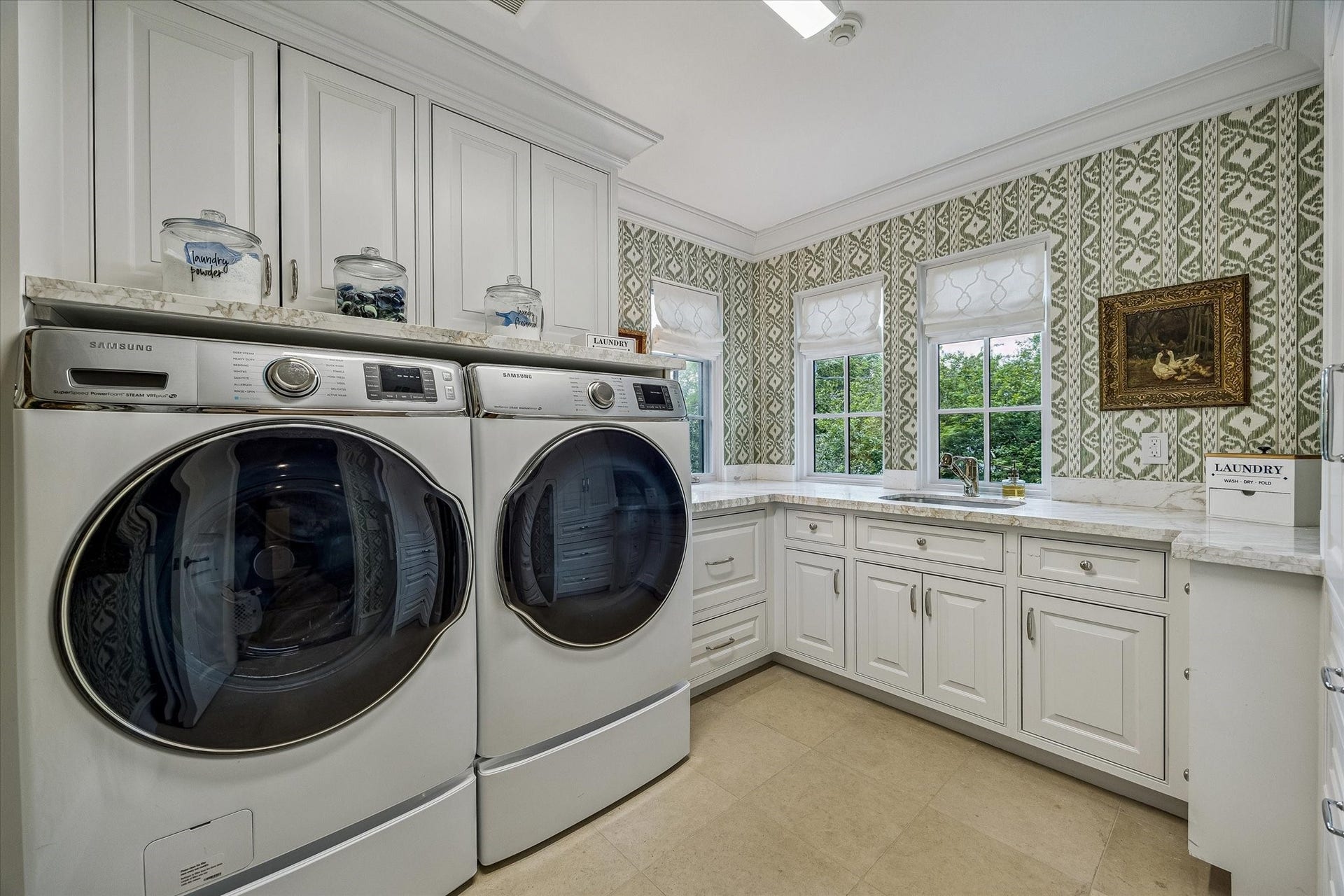 2158 Chilton Road, Houston, TX 77019 The utility room combines style and function with tile flooring, marble countertops, stainless steel sink, and Samsung washer and dryer. Green Rapallo wallpaper and ample storage make this space both practical and inviting.