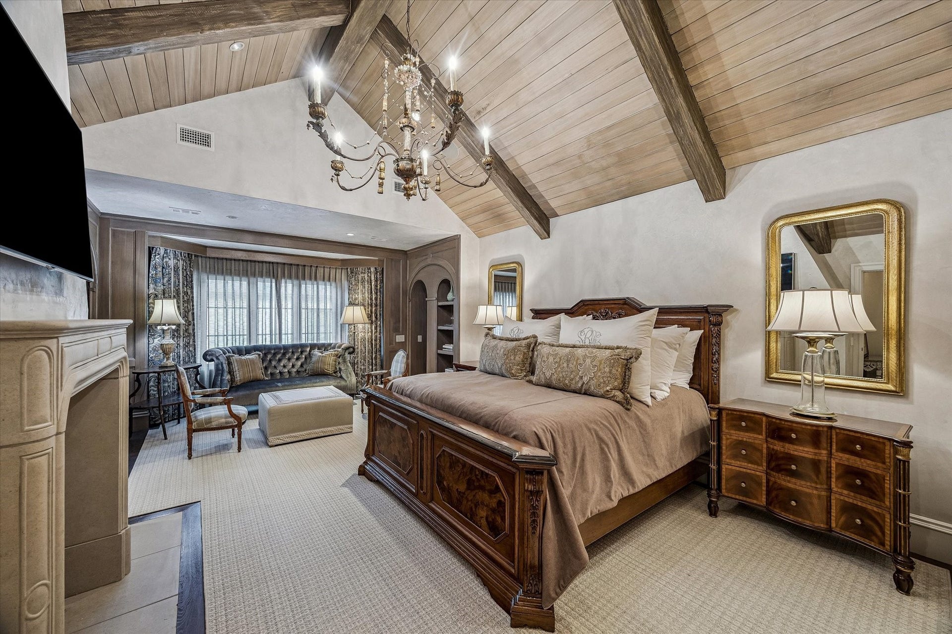 2158 Chilton Road, Houston, TX 77019 The primary bedroom is accessed through the study or front hallway and is a serene retreat for owners. This room features vaulted, beam-accented wood ceilings, Segreto plaster walls, and a cast stone fireplace. Custom remote-controlled draperies, designer lighting, and in-ceiling speakers create a luxurious and comfortable living space.