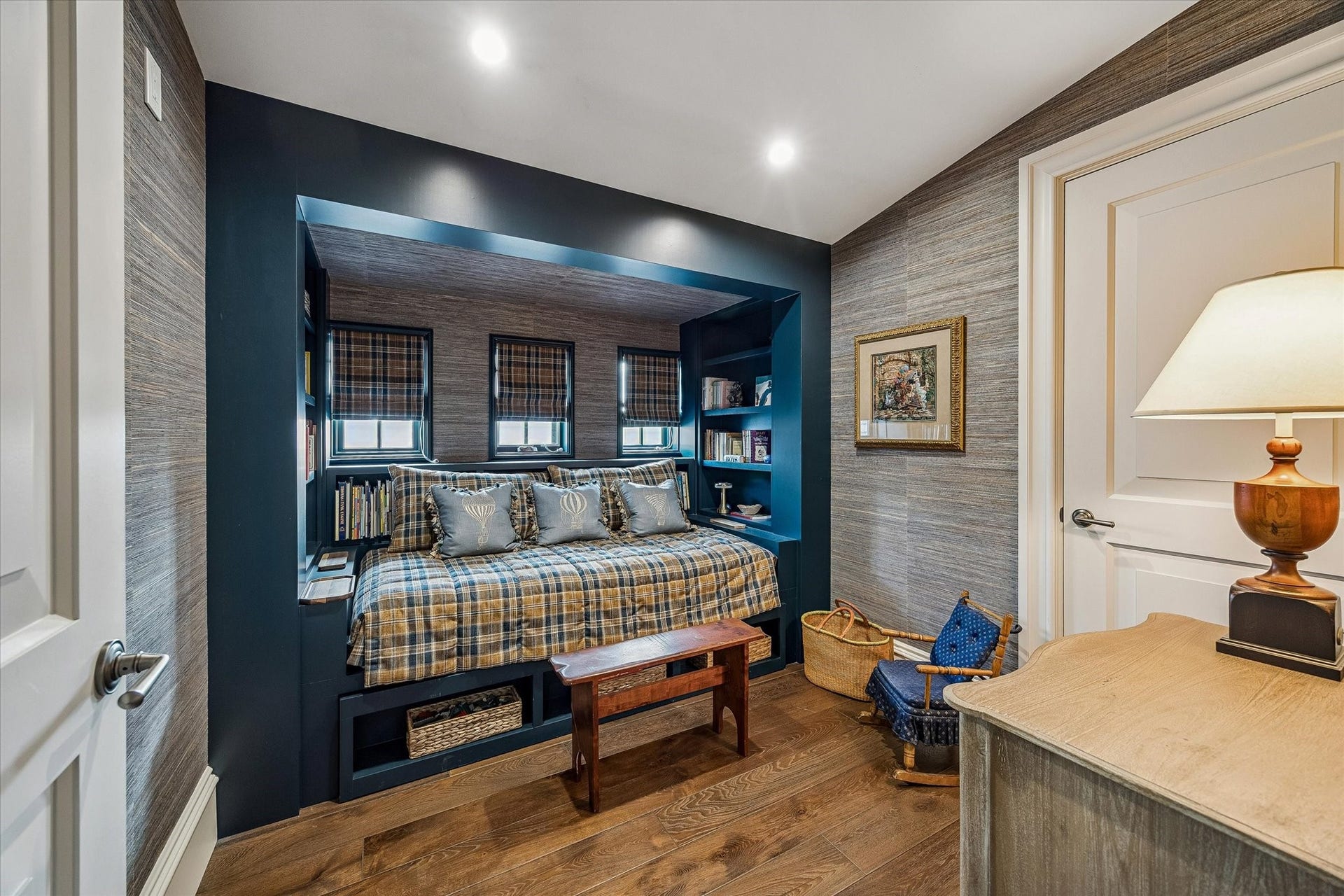 2158 Chilton Road, Houston, TX 77019 The third-floor bunk room offers a cozy and thoughtfully designed retreat with built-in daybed space, custom shelving, and rich grasscloth wallcovering. Warm hardwood floors and western-facing windows create a comfortable, light-filled space perfect for guests or relaxed lounging.