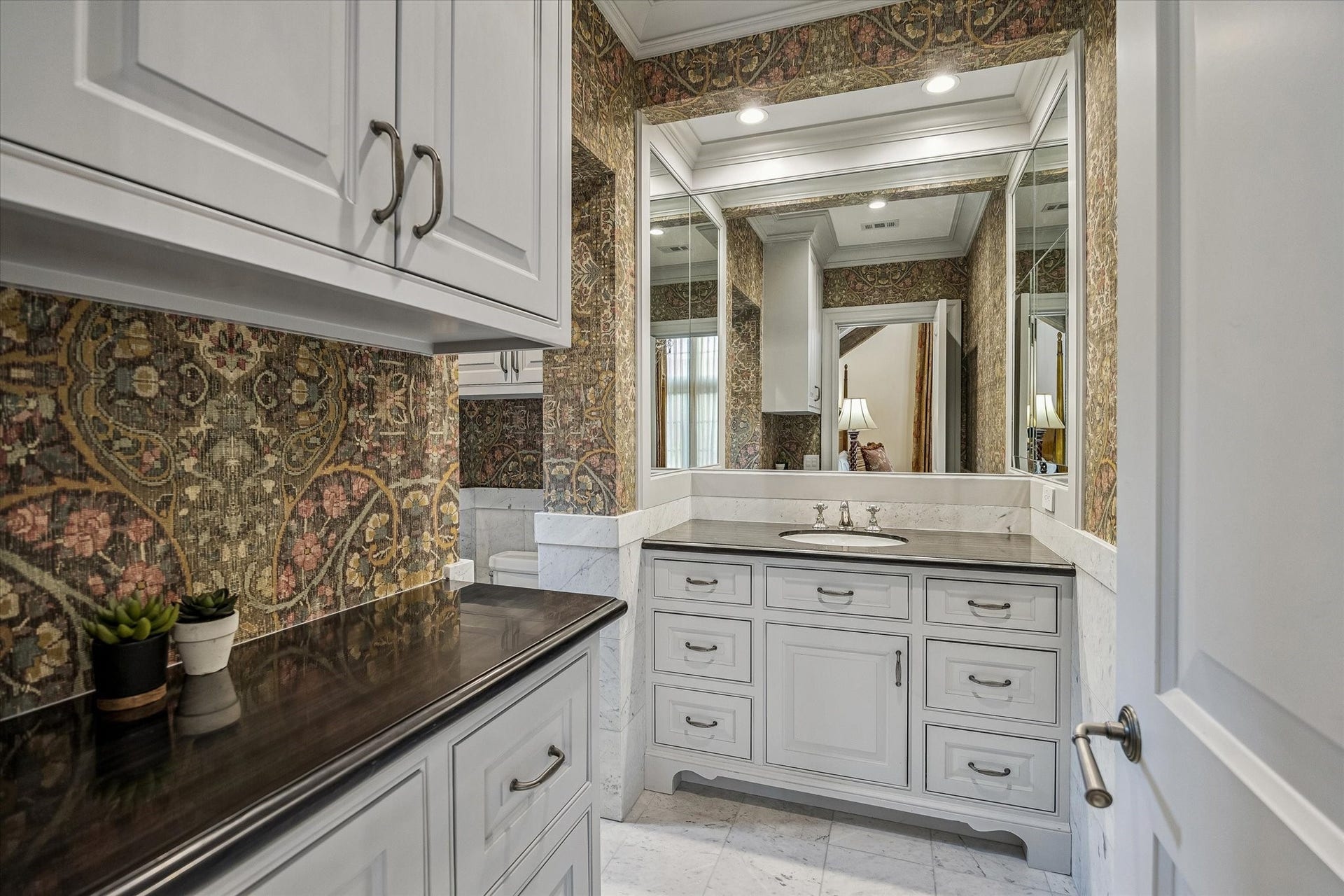 2158 Chilton Road, Houston, TX 77019 This large ensuite bath features marble floors and countertops, a walk-in shower with bench seating, and elegant designer wallcoverings, this ensuite provides both luxury and practicality for guests.