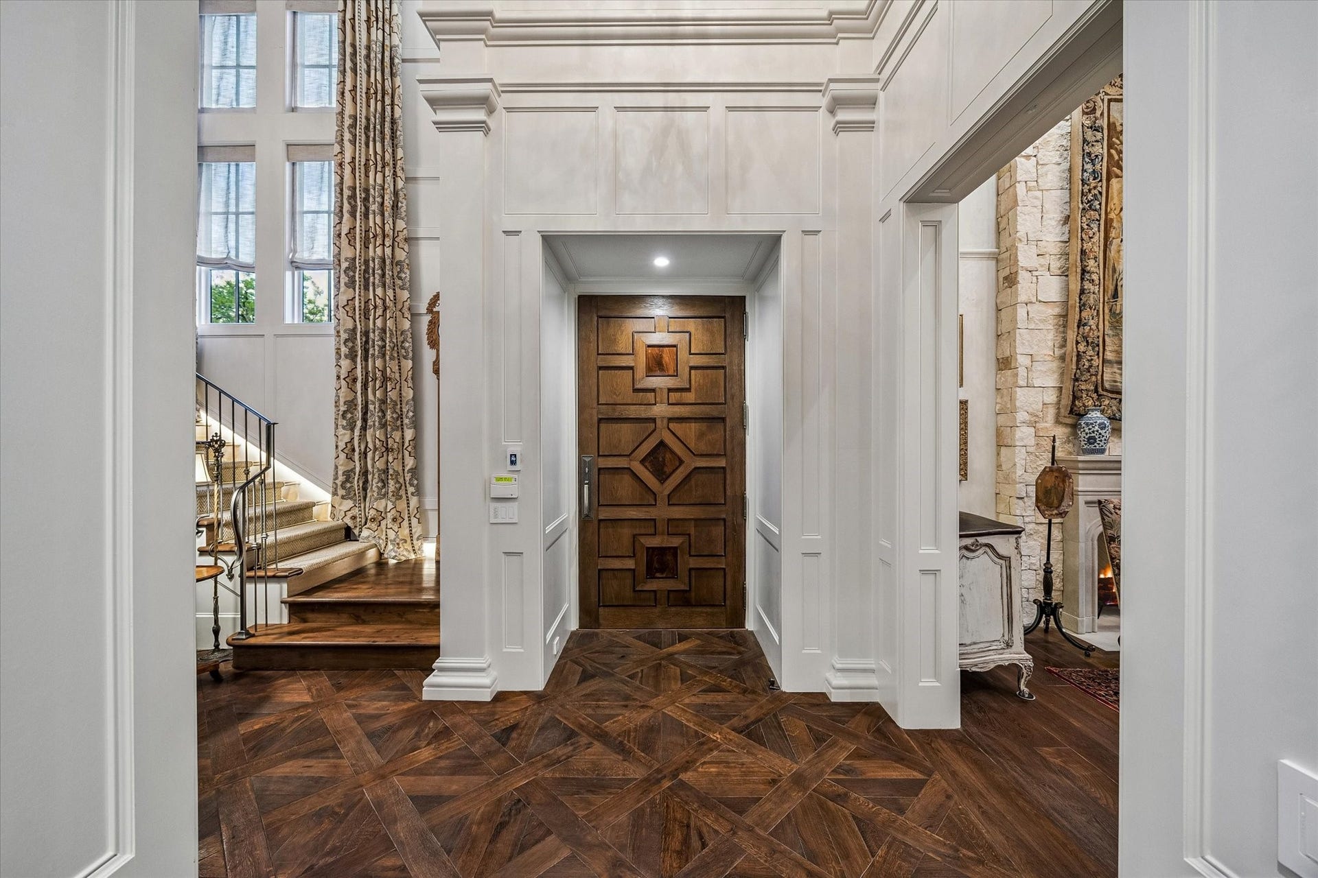 2158 Chilton Road, Houston, TX 77019 The elegant foyer, featuring Versailles parquet hardwood flooring, serves as a grand introduction to the home. Cased openings provide access to the formal living room, family room, and library, while the custom metal-railed staircase leads gracefully to the upper floors.