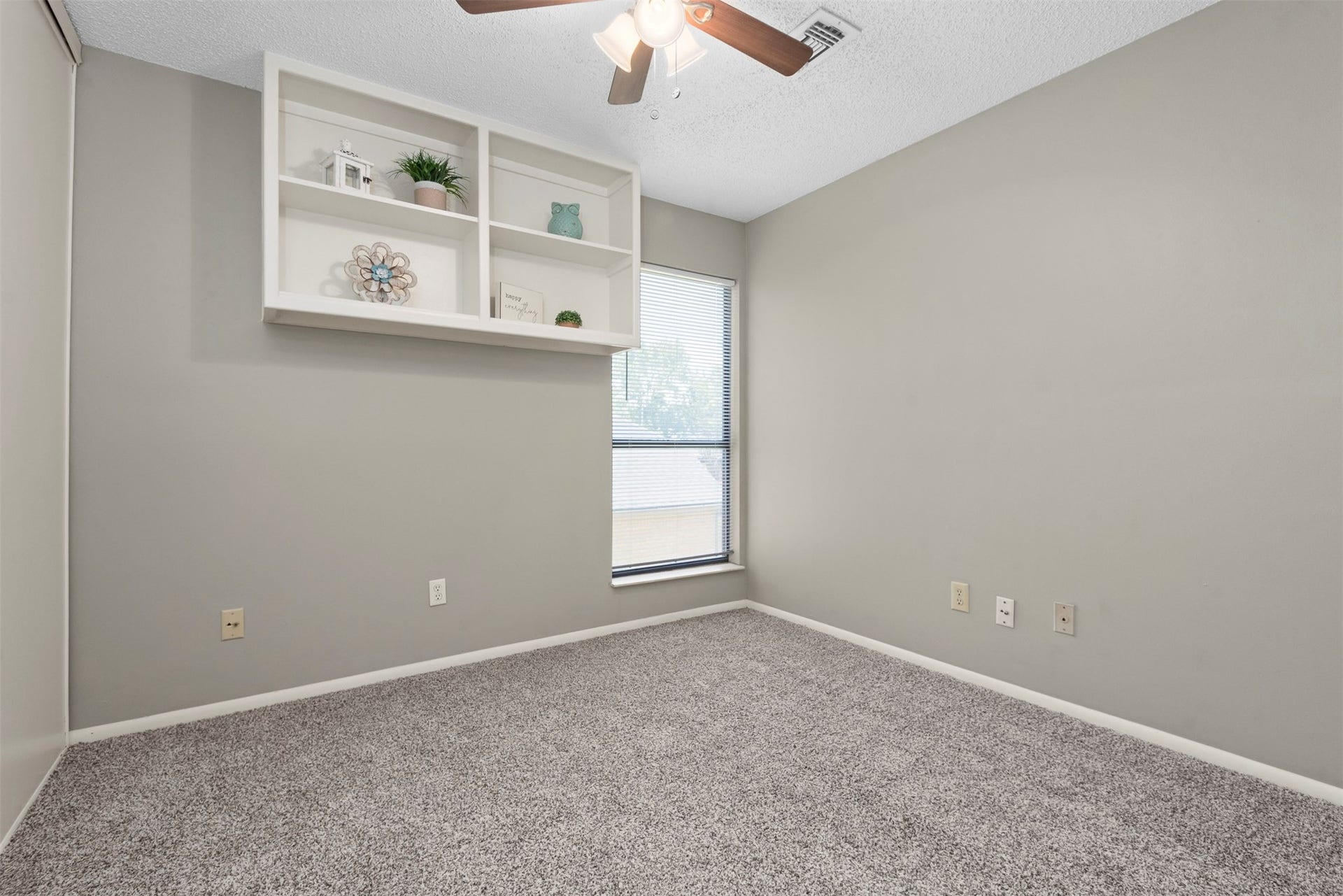 The first of the secondary bedrooms has shelving, a spacious closet and a ceiling fan.