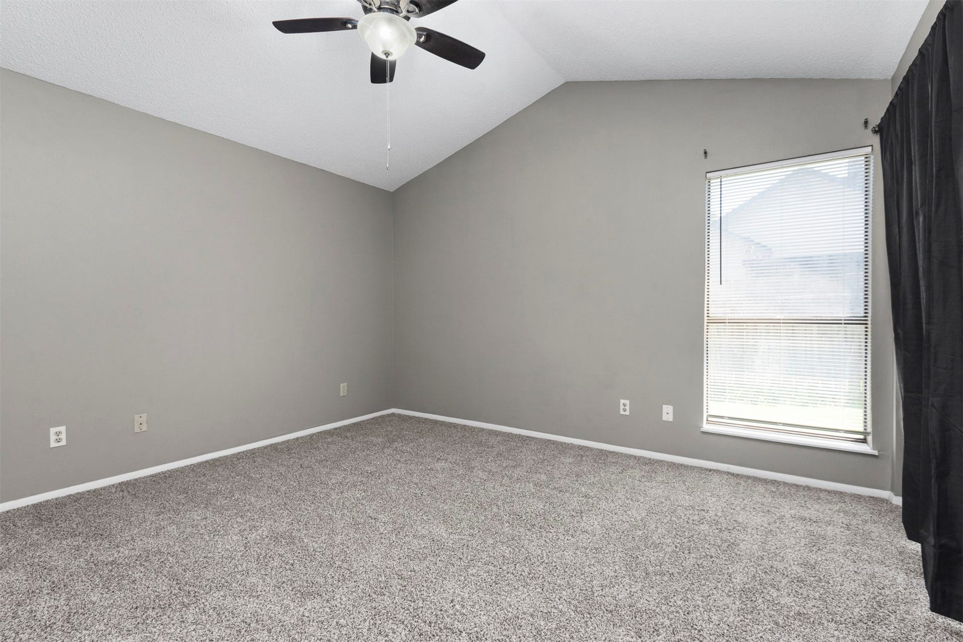 The primary bedroom has a vaulted ceiling, a sliding door to the patio, fresh neutral paint, fresh carpet and natural light.