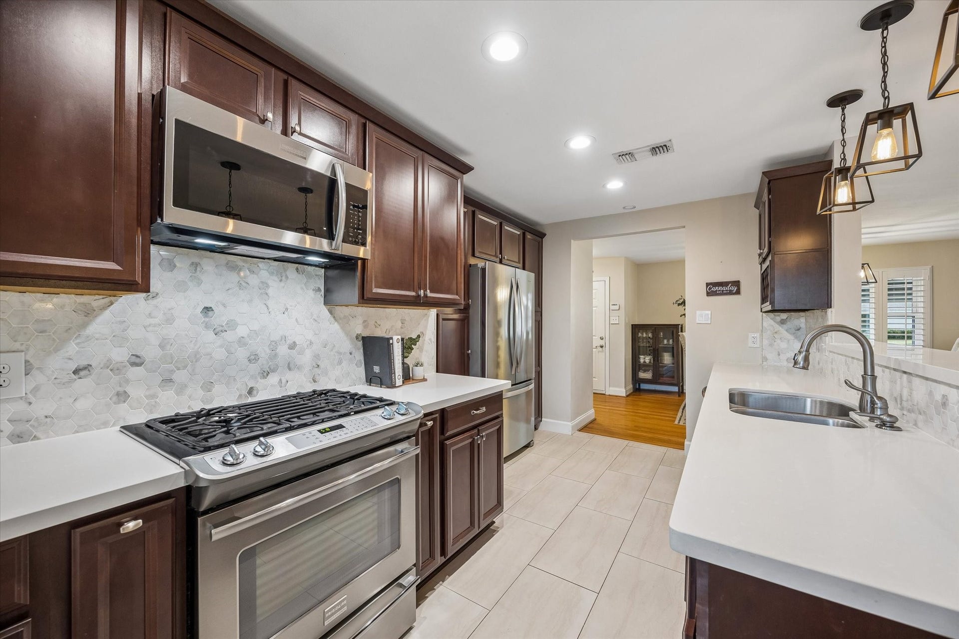 2318 Cheshire Lane, Houston, TX 77018 Gas range, microwave and surrounding counters create a convenient cooking area. Cabinet storage keeps essentials nearby, while the kitchen's open connection to adjacent rooms makes serving meals straightforward.
