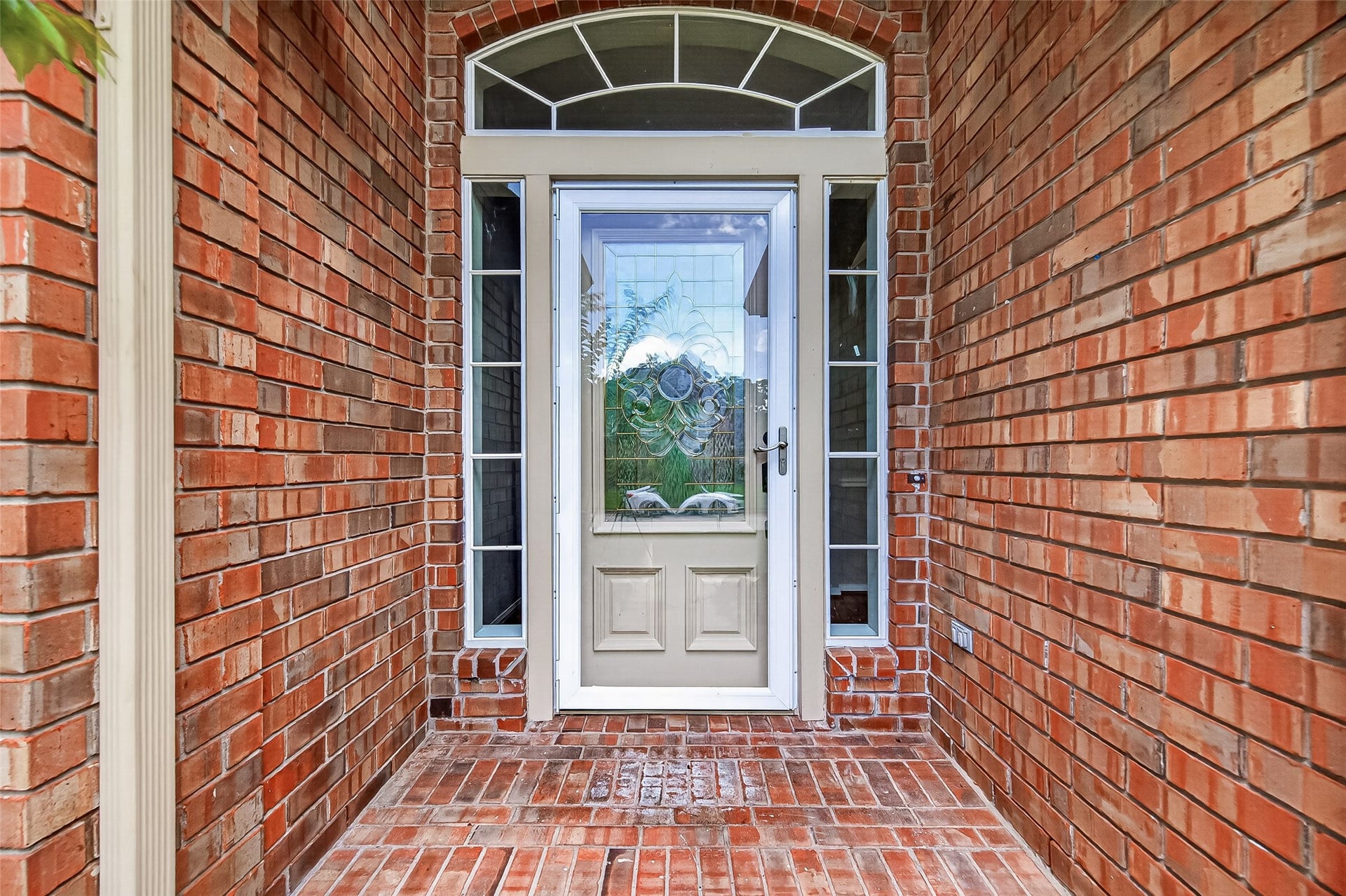 12823 Lady Jane Court, Houston, TX 77044 Charming brick entryway with a decorative glass front door and sidelights, offering a warm and inviting welcome.