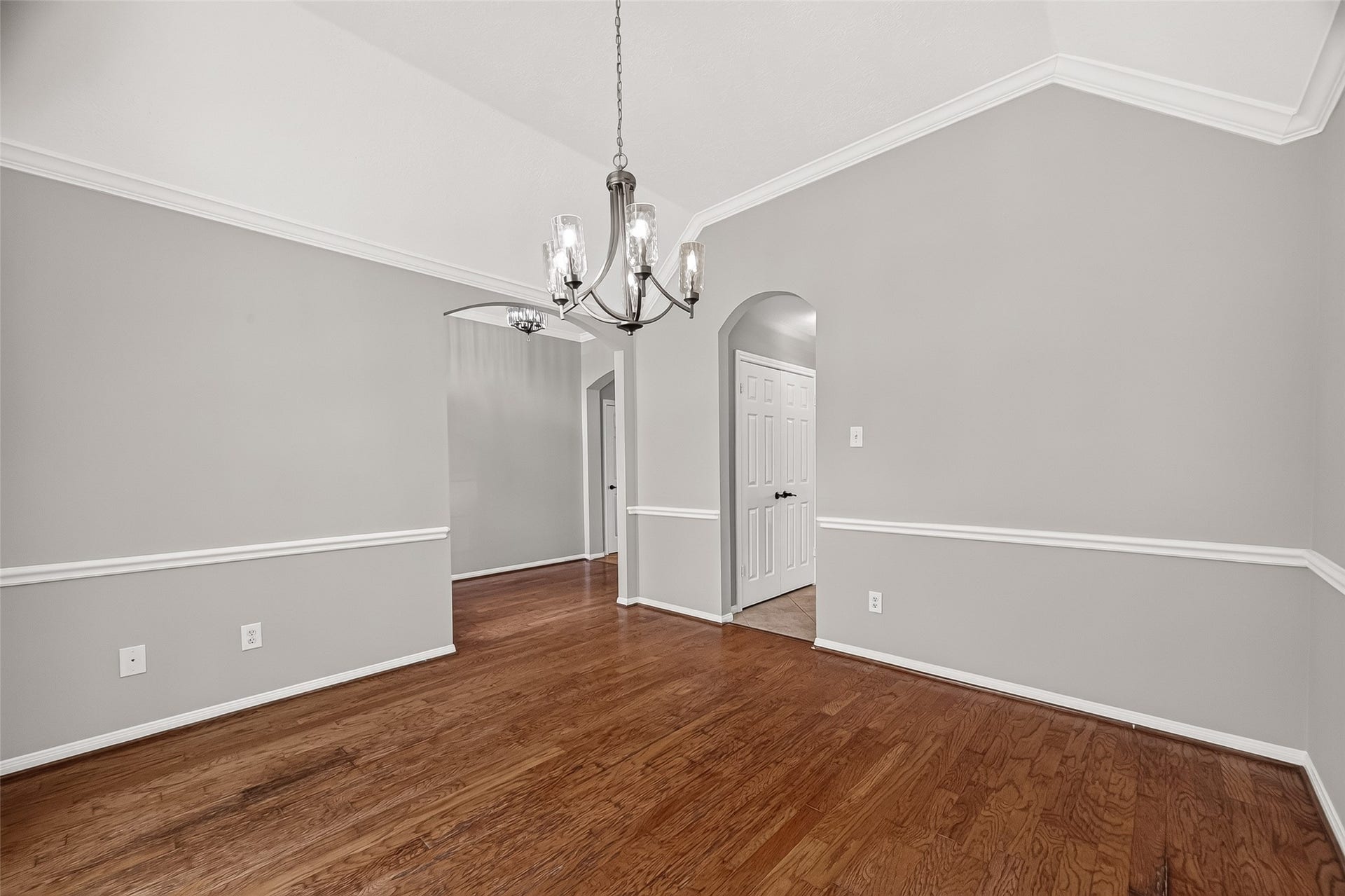 12823 Lady Jane Court, Houston, TX 77044 Elegant dining area with hardwood floors, a contemporary chandelier, and stylish wainscoting, creating a sophisticated space for entertaining.