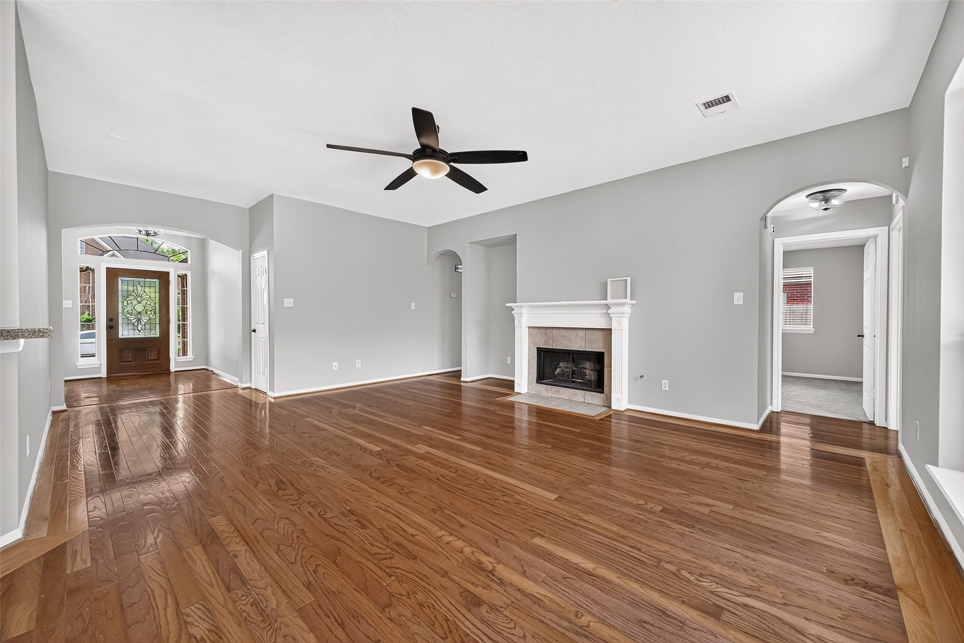 12823 Lady Jane Court, Houston, TX 77044 Spacious living room with gleaming hardwood floors, a cozy fireplace, and abundant natural light from large windows, perfect for relaxation and entertaining.