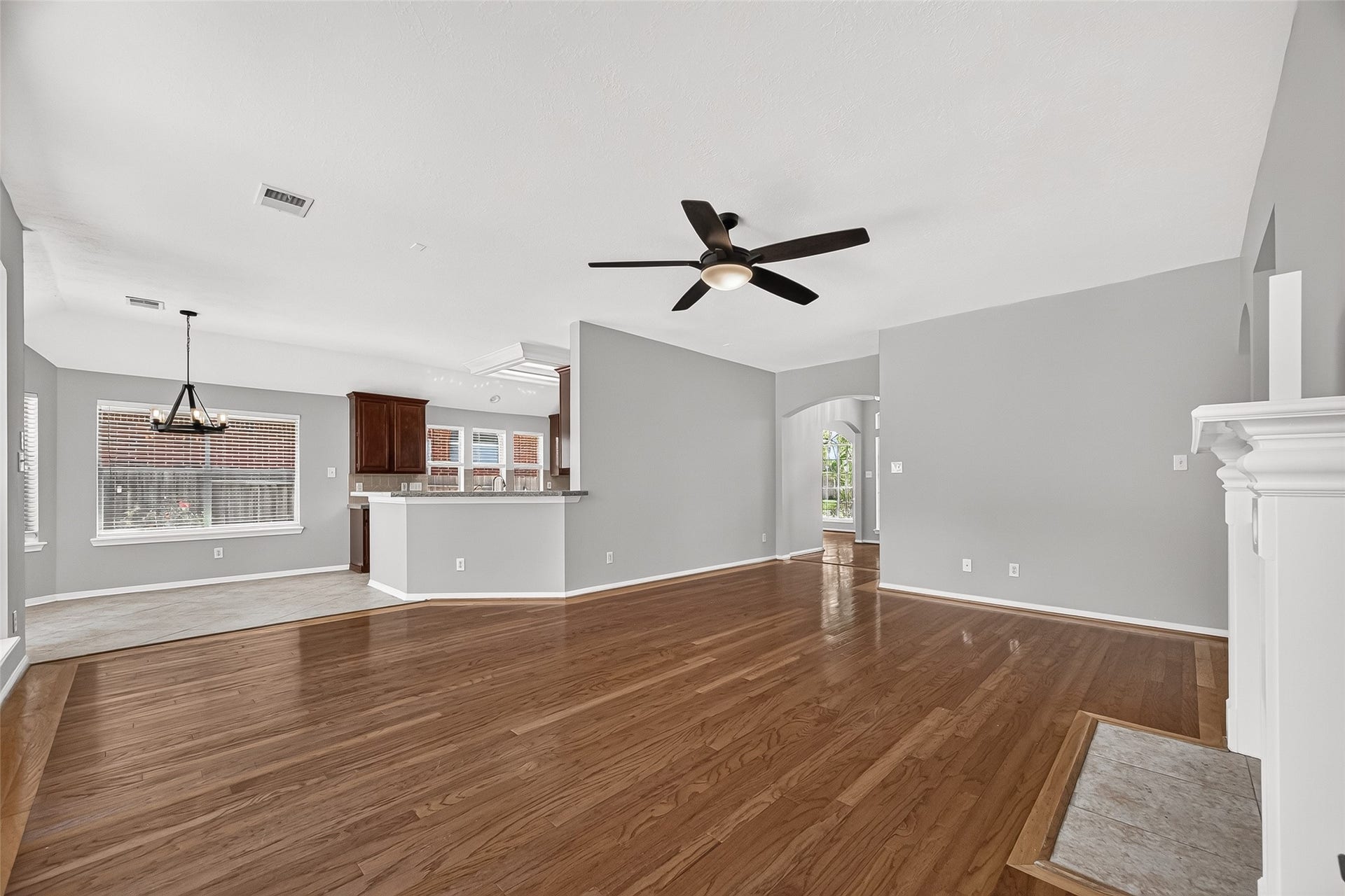 12823 Lady Jane Court, Houston, TX 77044 Spacious open-concept living area with sleek hardwood floors, modern ceiling fan, and abundant natural light, seamlessly connecting to a bright kitchen and dining space.
