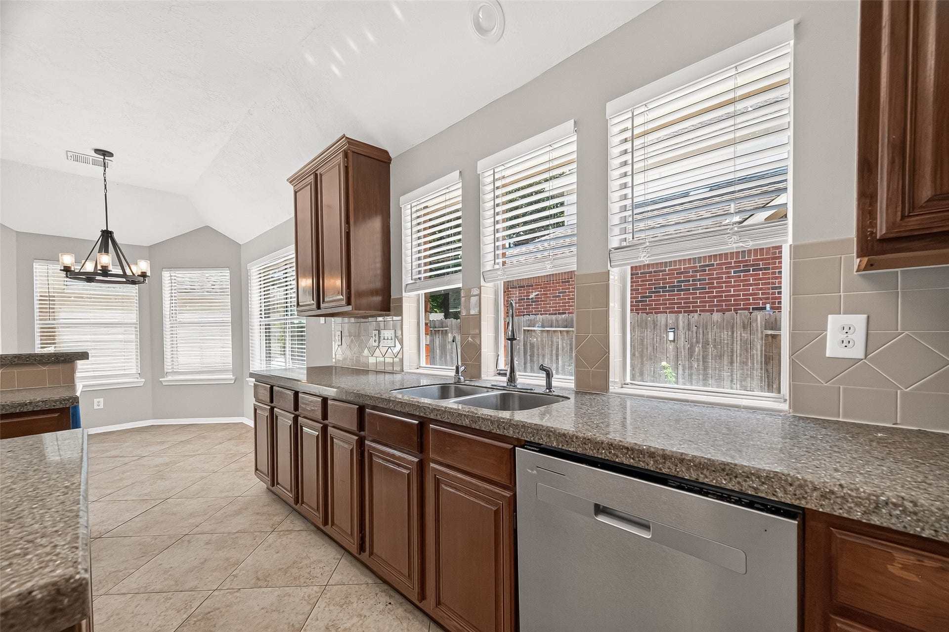 12823 Lady Jane Court, Houston, TX 77044 Bright kitchen featuring expansive windows, modern stainless steel fixtures, and rich wood cabinetry. The tiled backsplash and spacious countertops offer style and functionality, perfect for meal prep and entertaining.