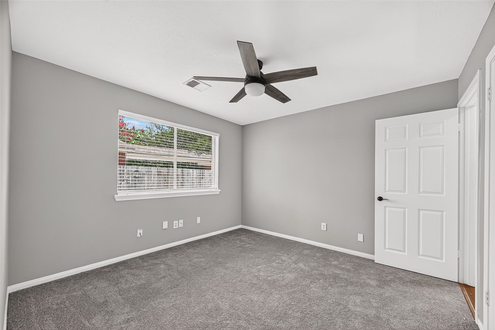 12823 Lady Jane Court, Houston, TX 77044 Bright and inviting bedroom featuring fresh gray walls, plush carpeting, and a modern ceiling fan, with ample natural light streaming through a large window.